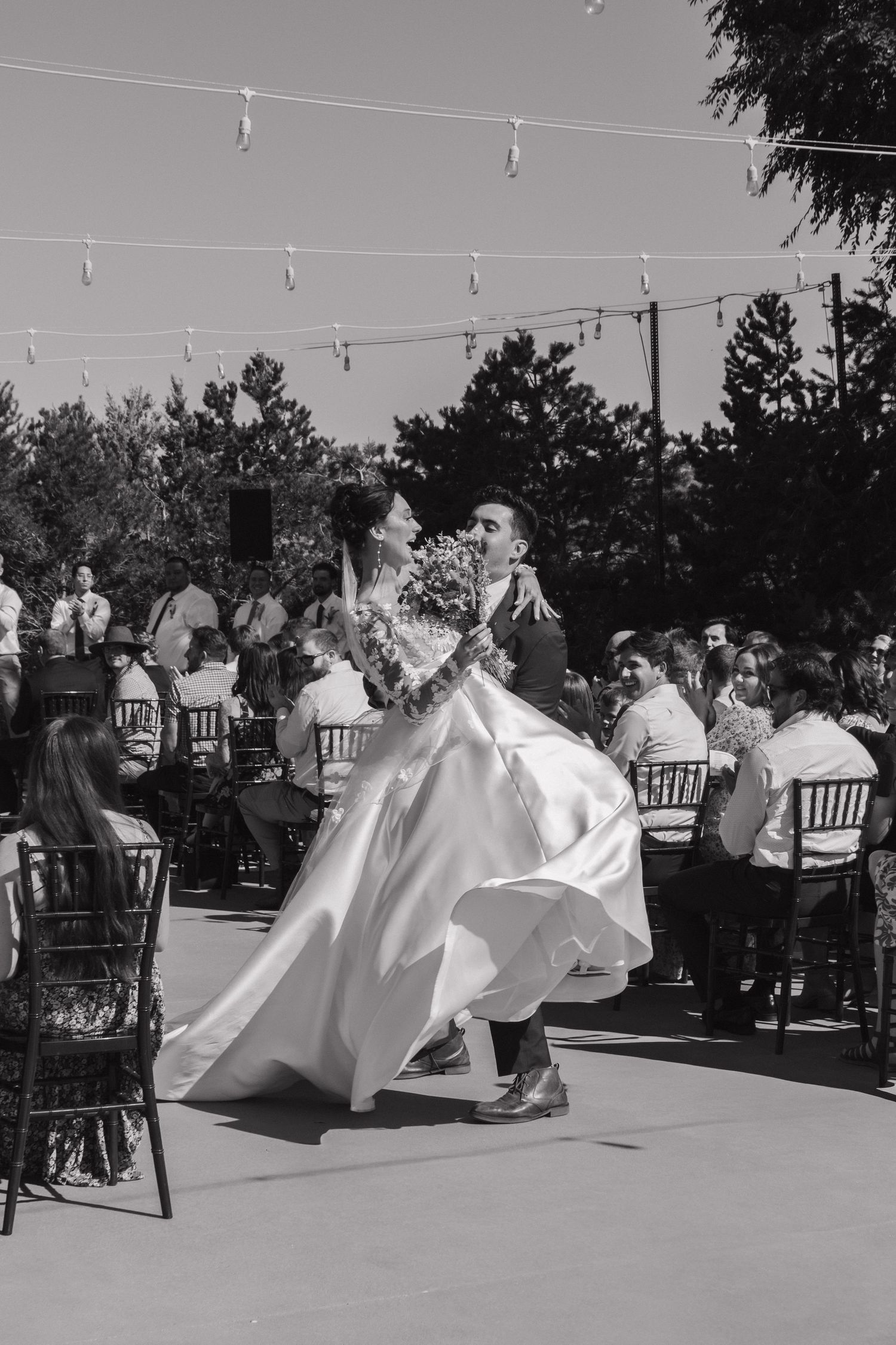 Wedding reception dance floor with flowing white dresses in motion under string lights.