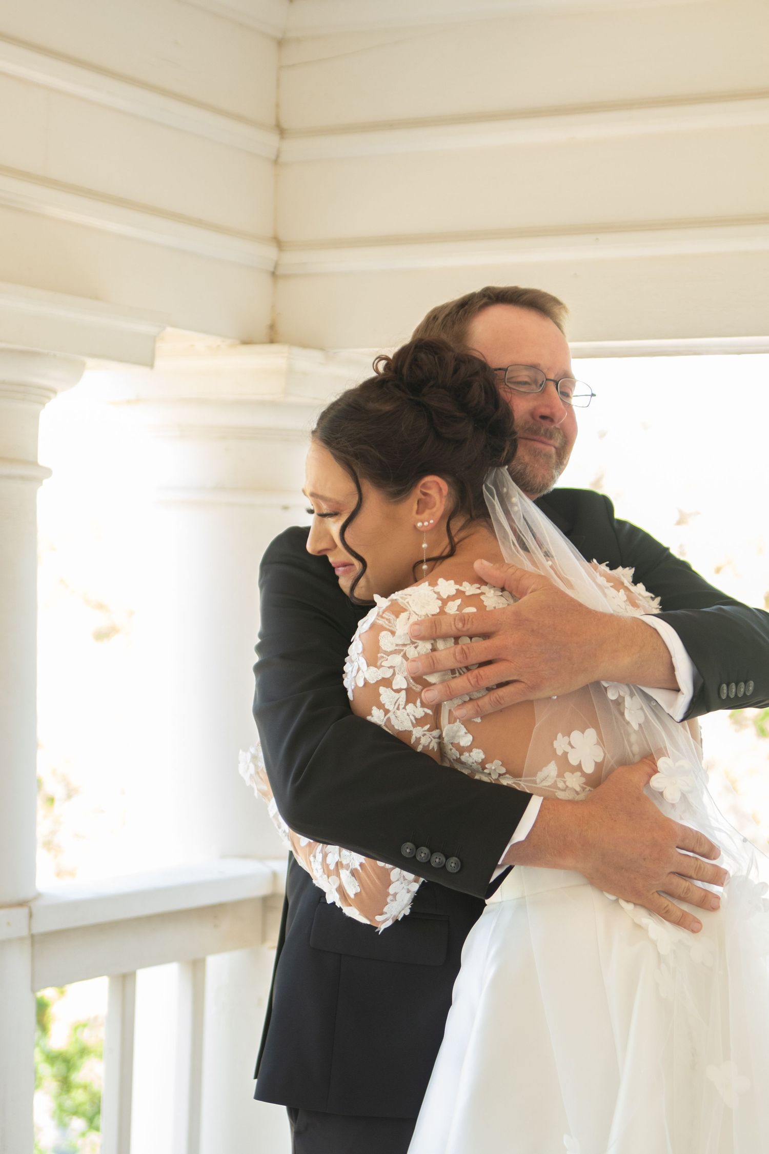 An emotional embrace during a wedding ceremony on a white wooden porch.