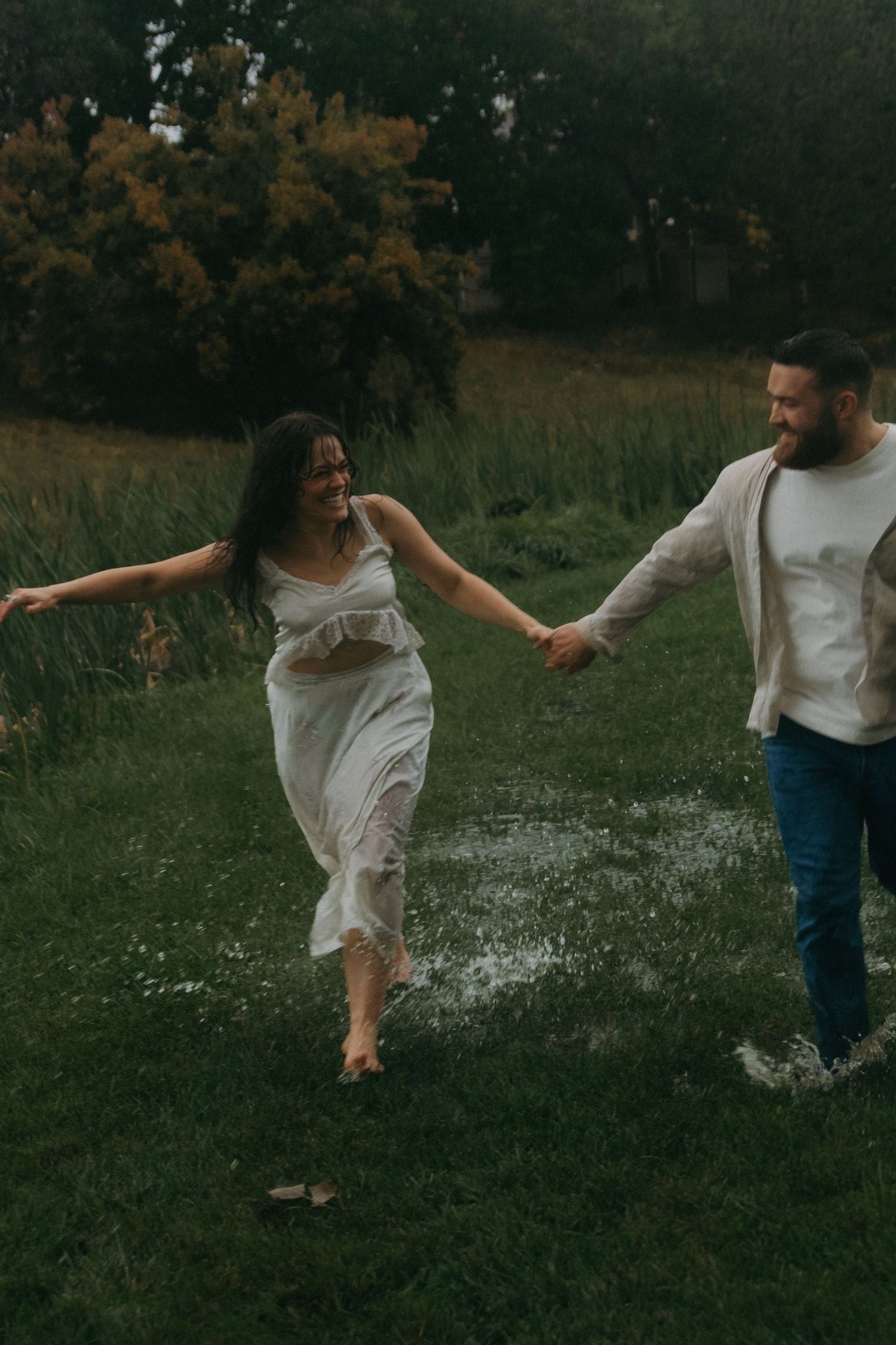 Two people dance together in a meadow filled with wildflowers at dusk.