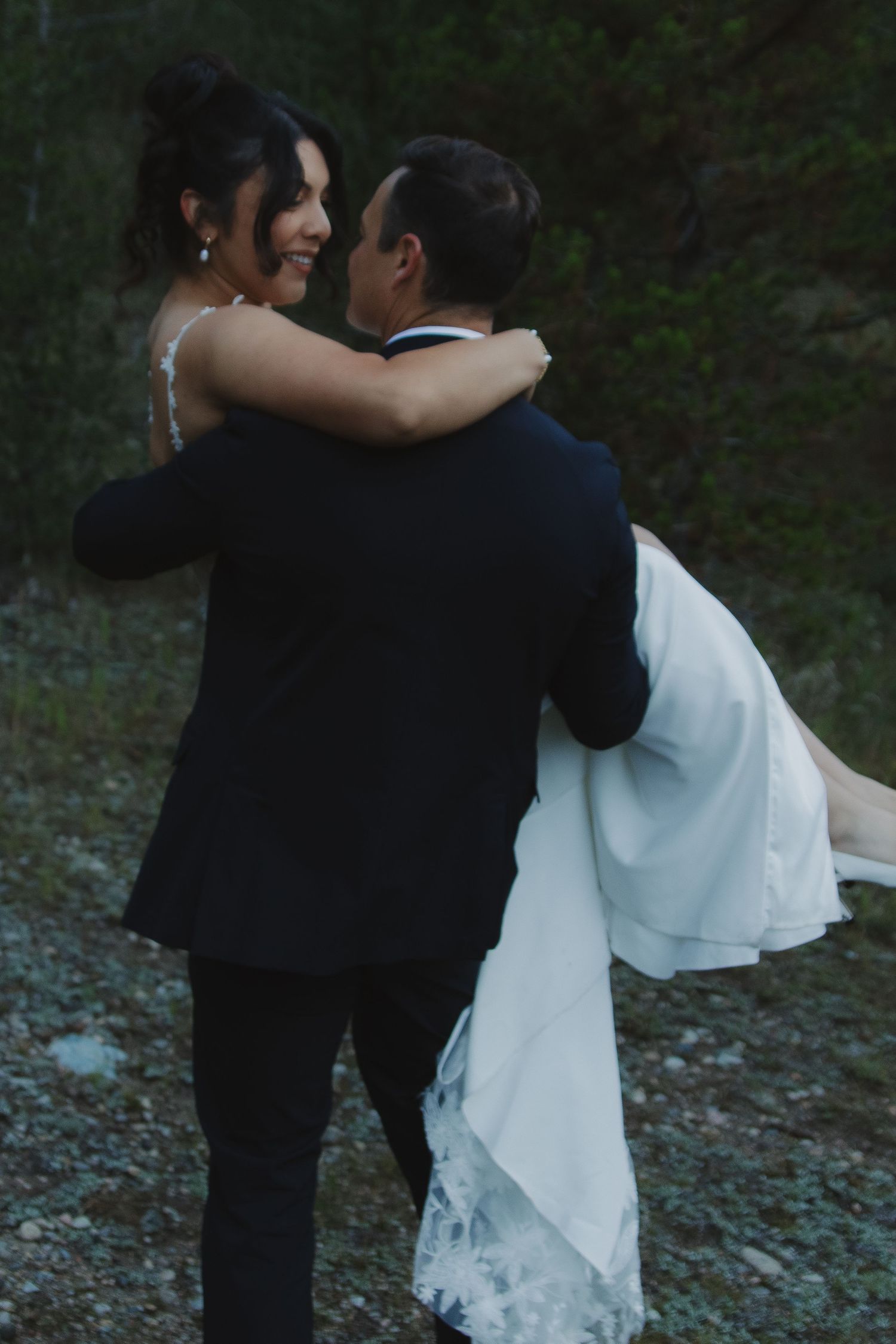 Newlyweds dance together against a darkening outdoor backdrop.