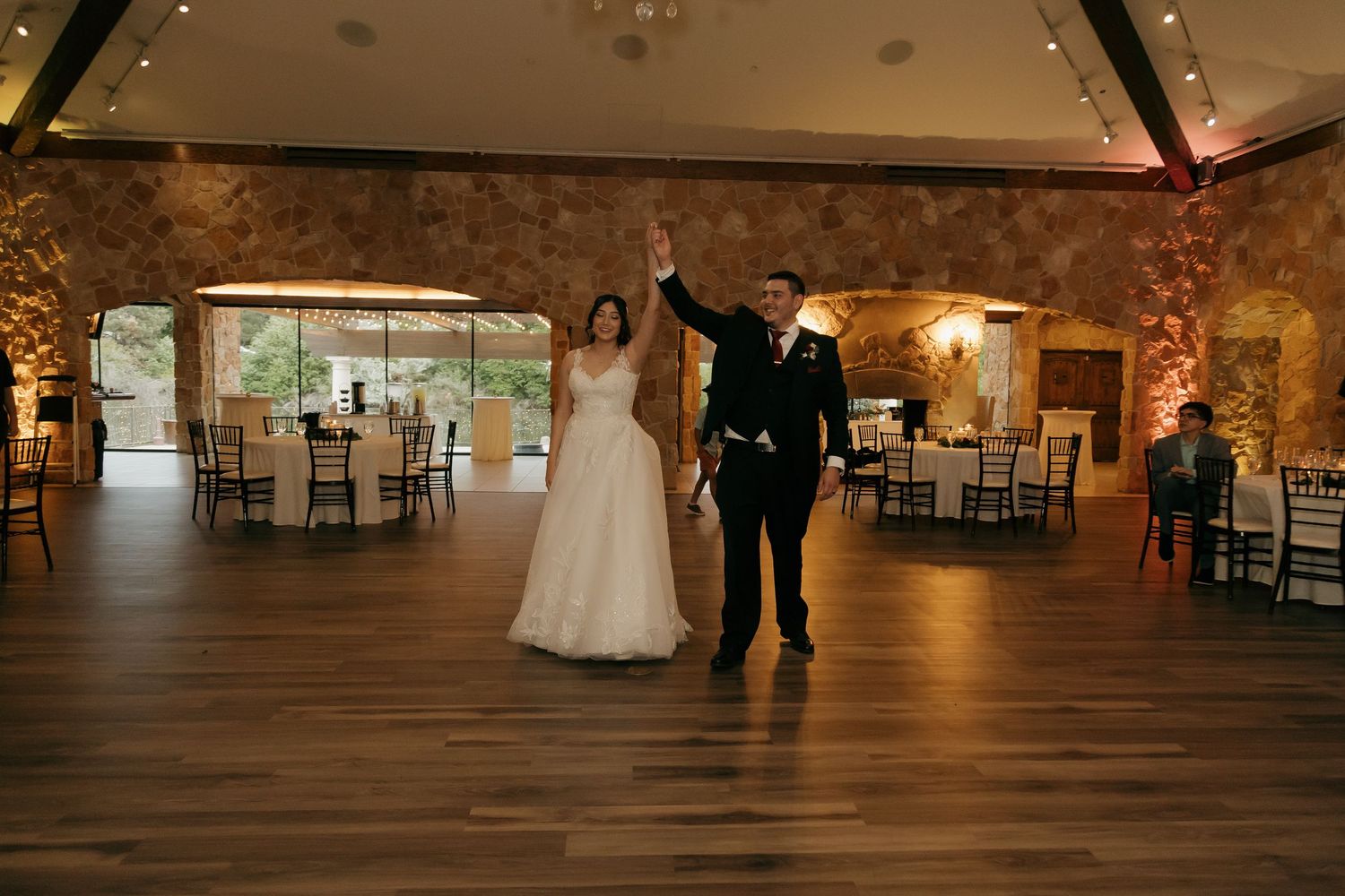 Bride and groom celebrate their first dance in a rustic stone wedding venue.