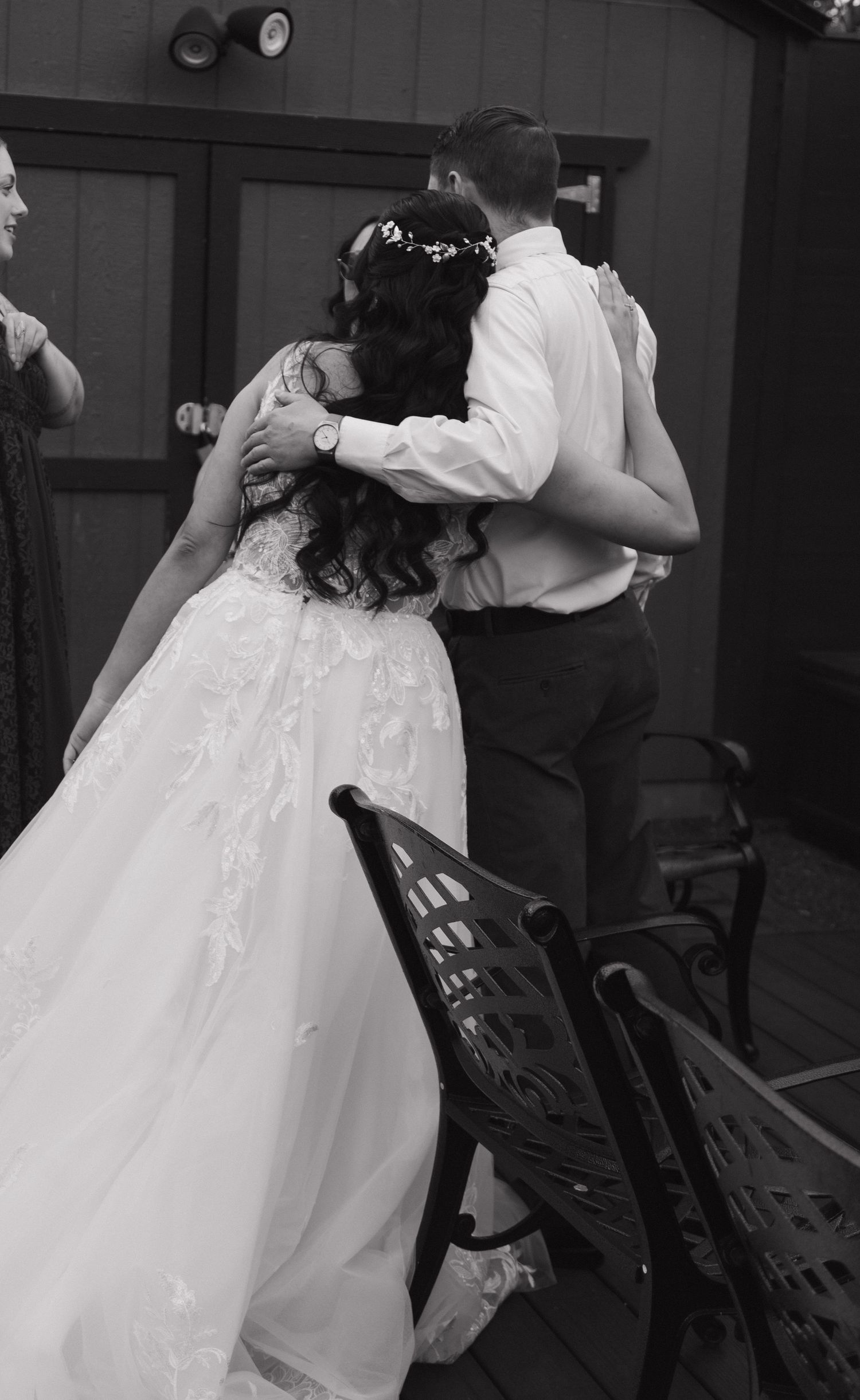 Black and white photo of bride and groom embracing tenderly outdoors at their wedding reception.