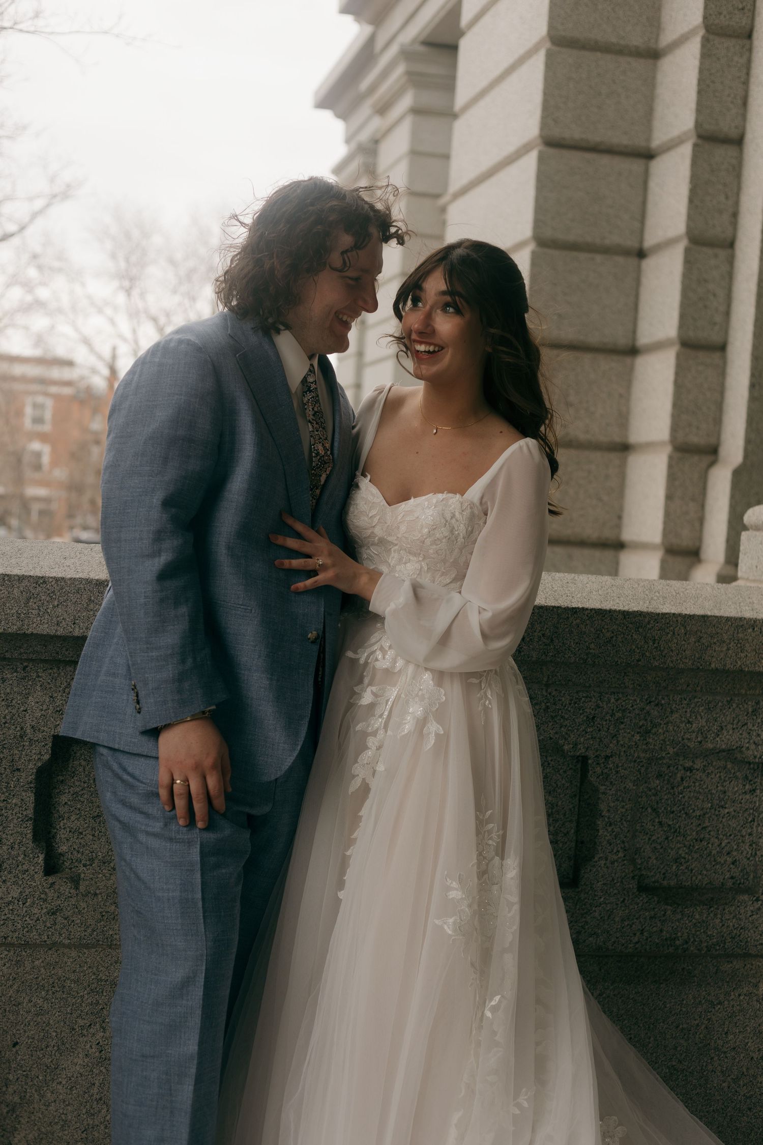 Romantic moment between newlyweds against stone architecture backdrop.