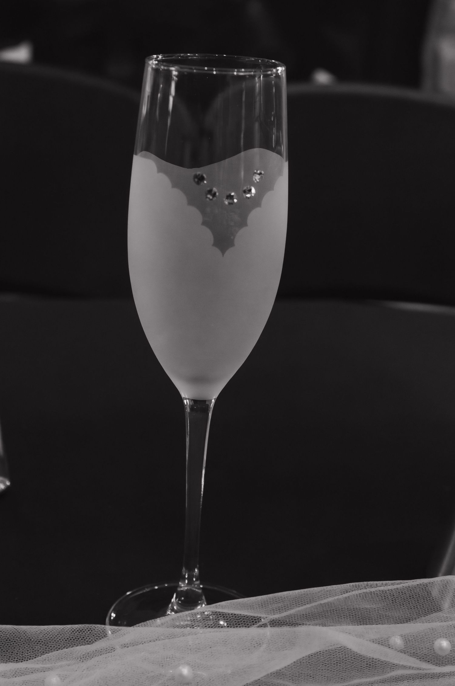 Champagne flute decorated with formal design sitting on delicate white tulle fabric.