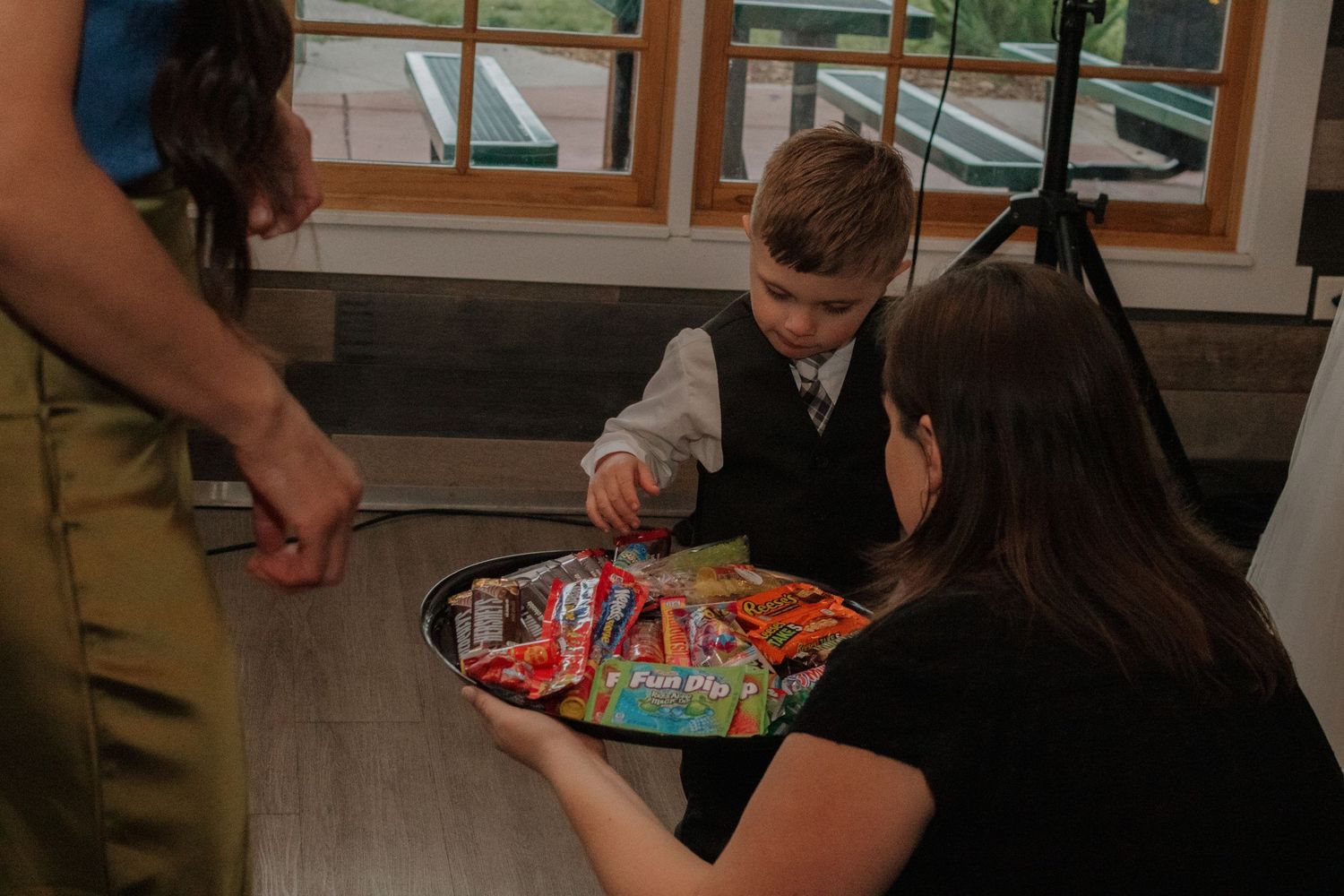 Small child reaching for candy from a tray being offered at a wedding reception.
