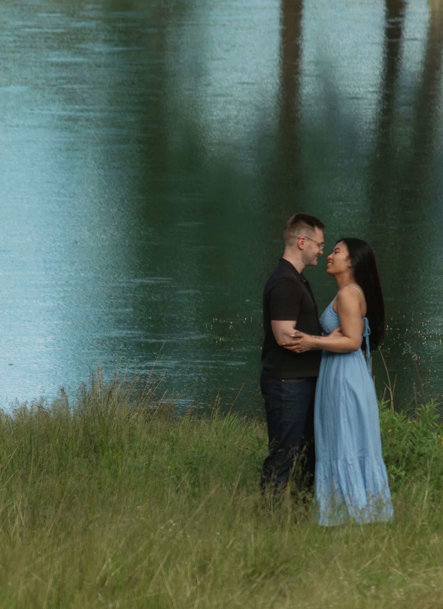 Romantic lakeside portrait with soft lighting and natural landscape elements.