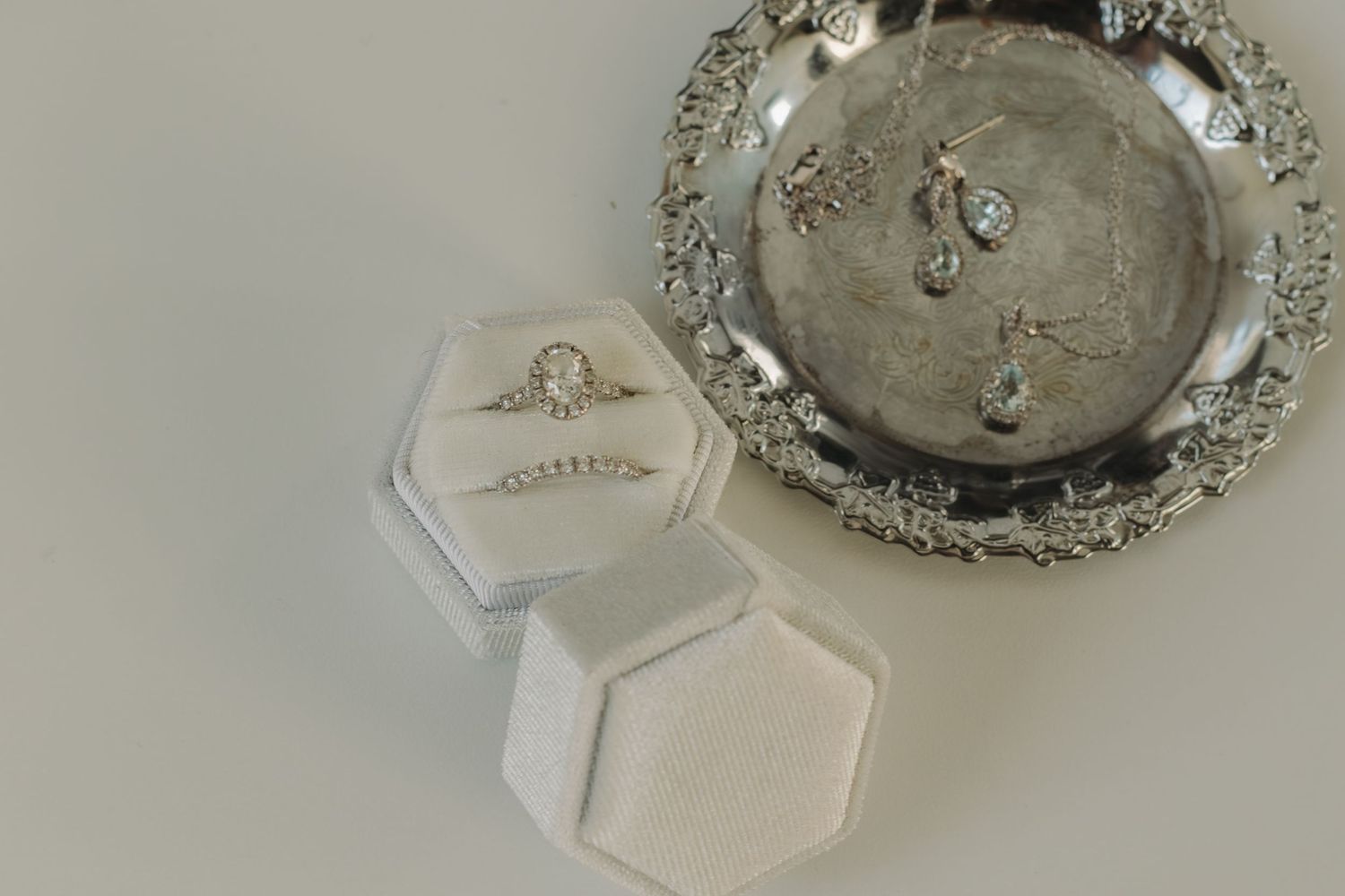 Wedding ring displayed in a hexagonal white box next to an ornate silver tray.