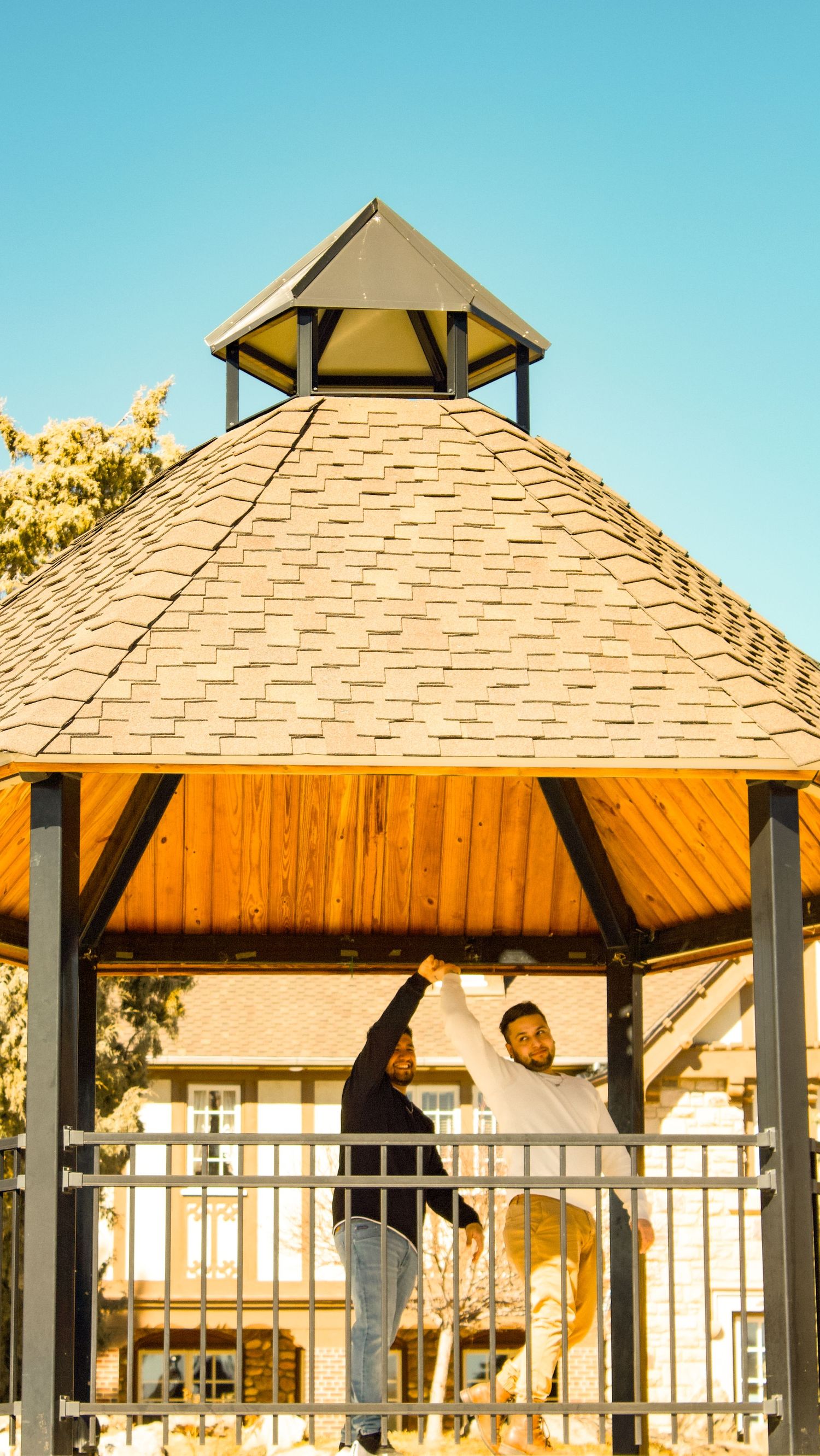Covered pavilion structure with wooden posts and shingled roof at sunny estate property.