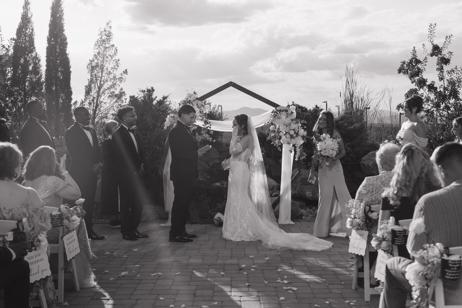 Black and white photo of bride and groom at outdoor wedding ceremony altar.