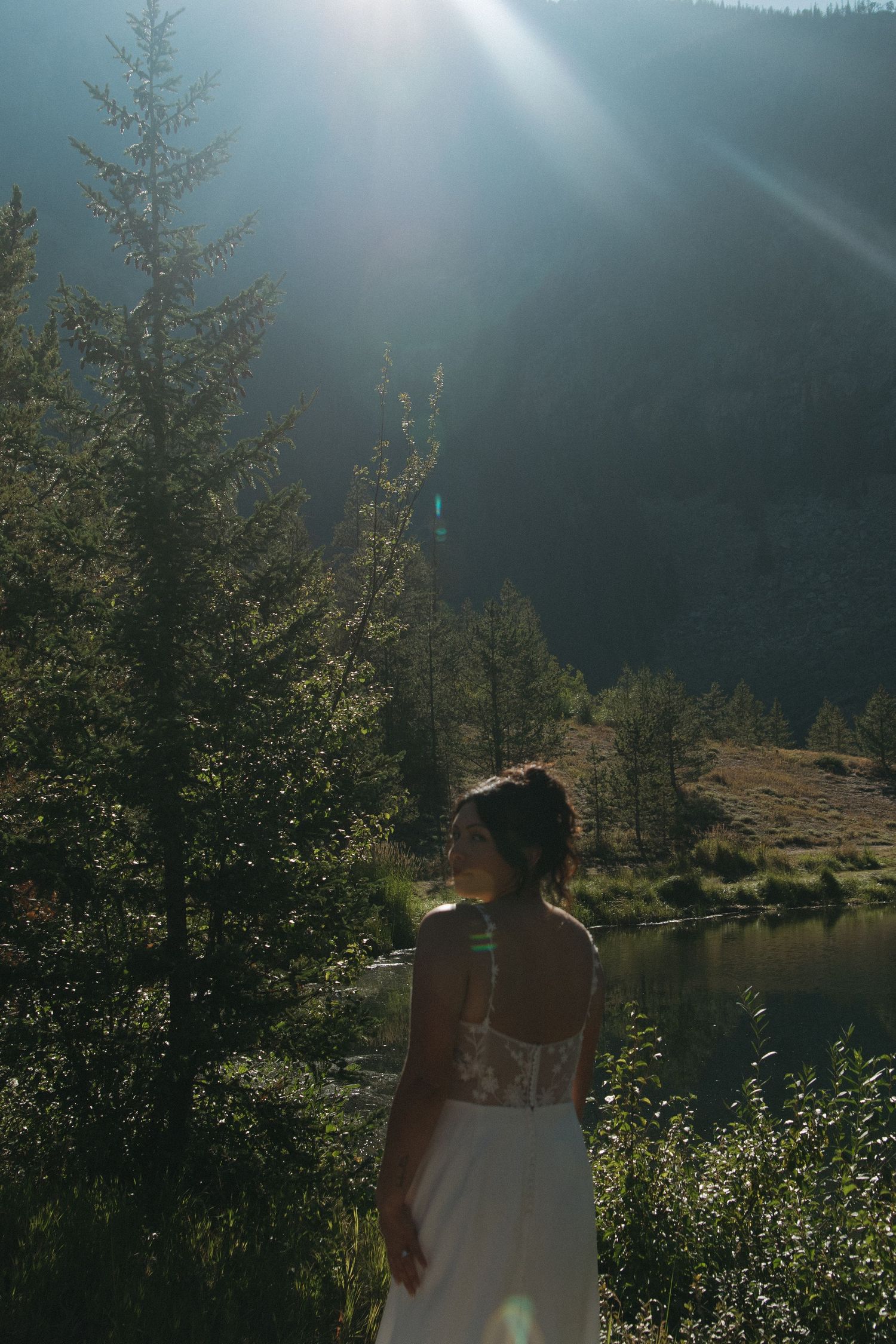 A scenic lakeside view at dusk with evergreen trees silhouetted against dramatic lighting.