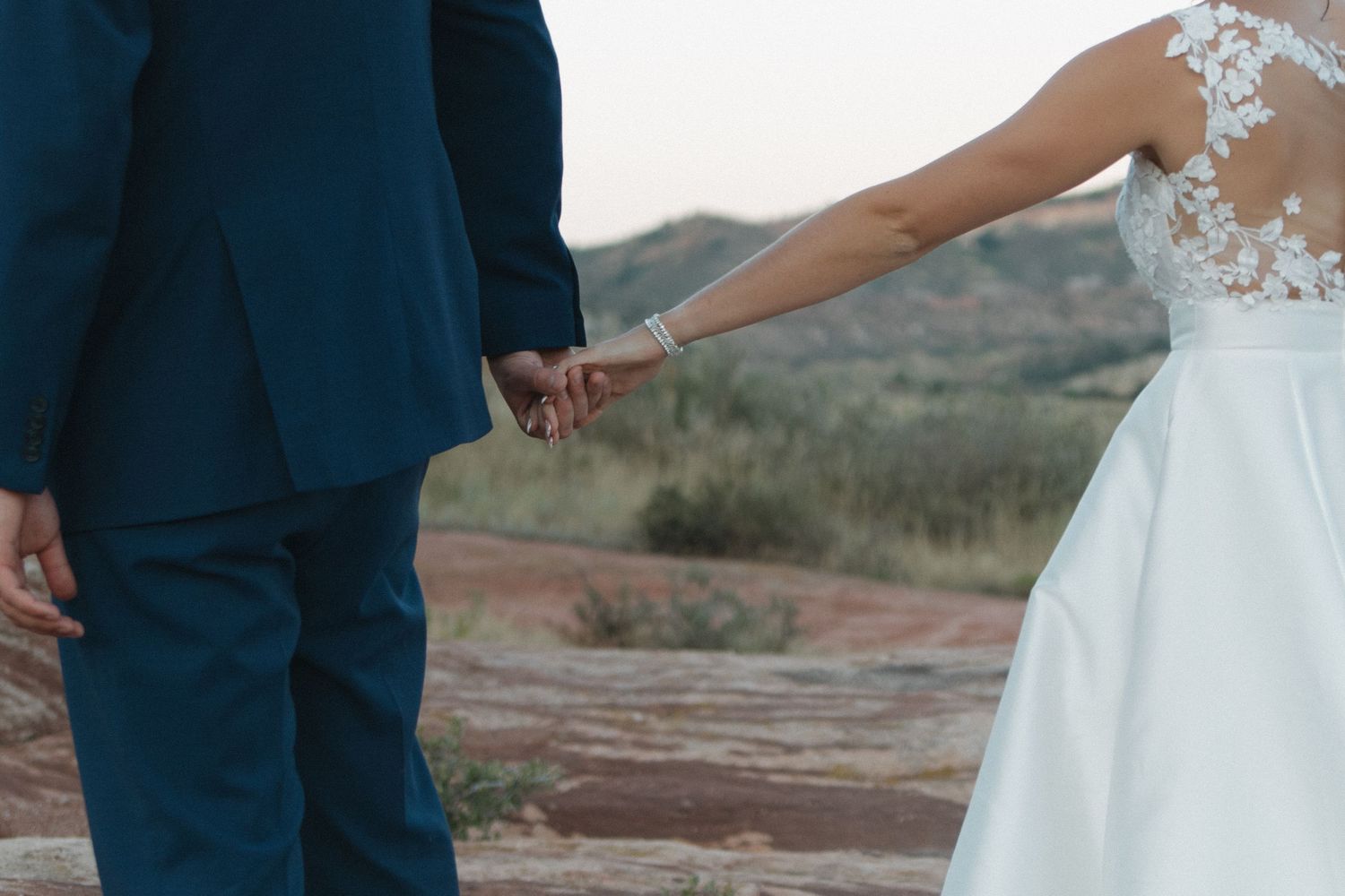 Couple shares romantic moment on red rocks during outdoor wedding portraits.