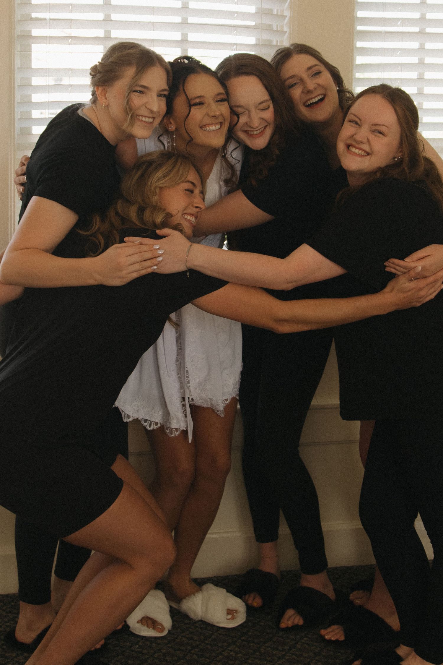 Bridesmaids in black attire huddling together for a fun group photo.