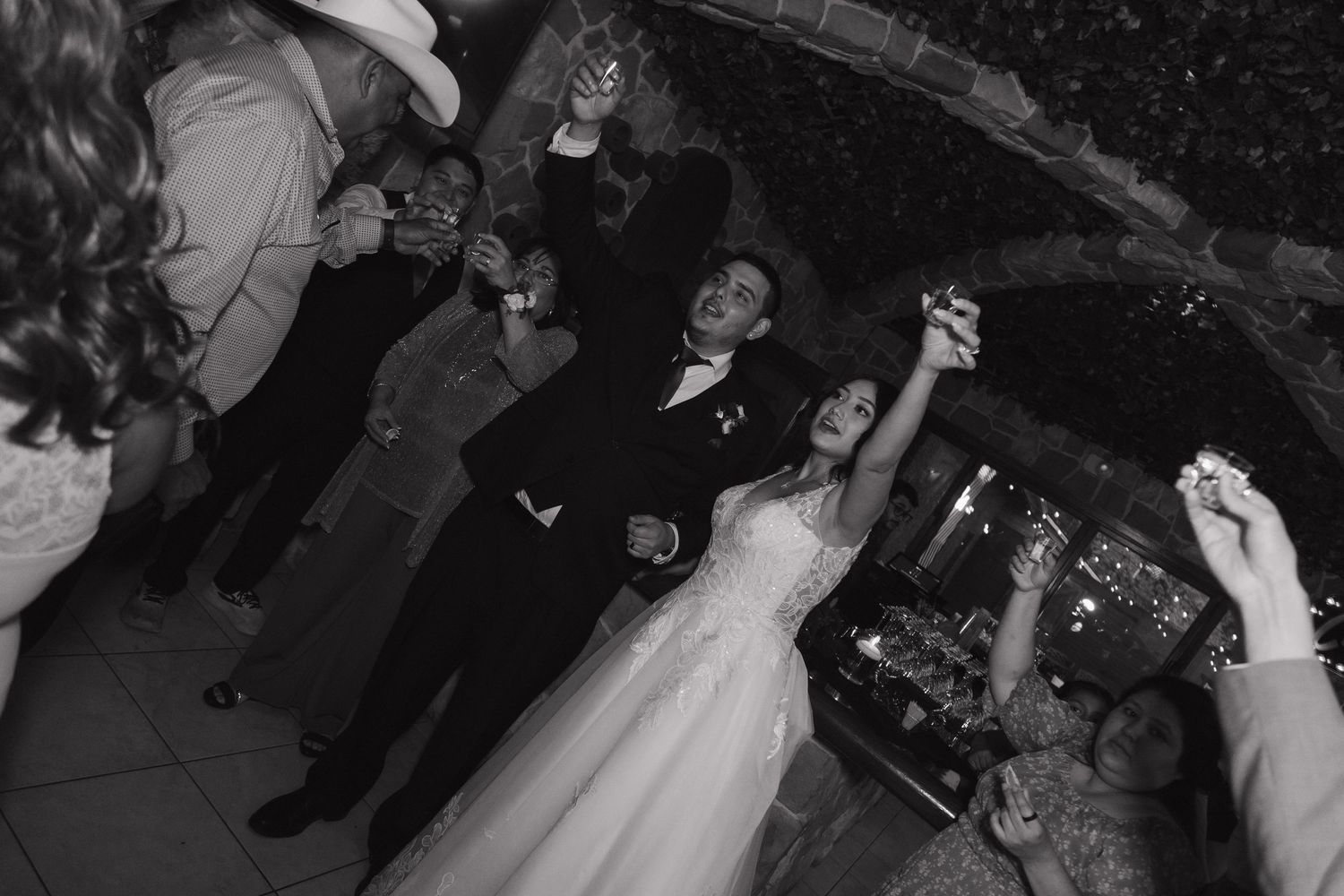 Bride and groom celebrate joyfully with guests on the outdoor dance floor at night.