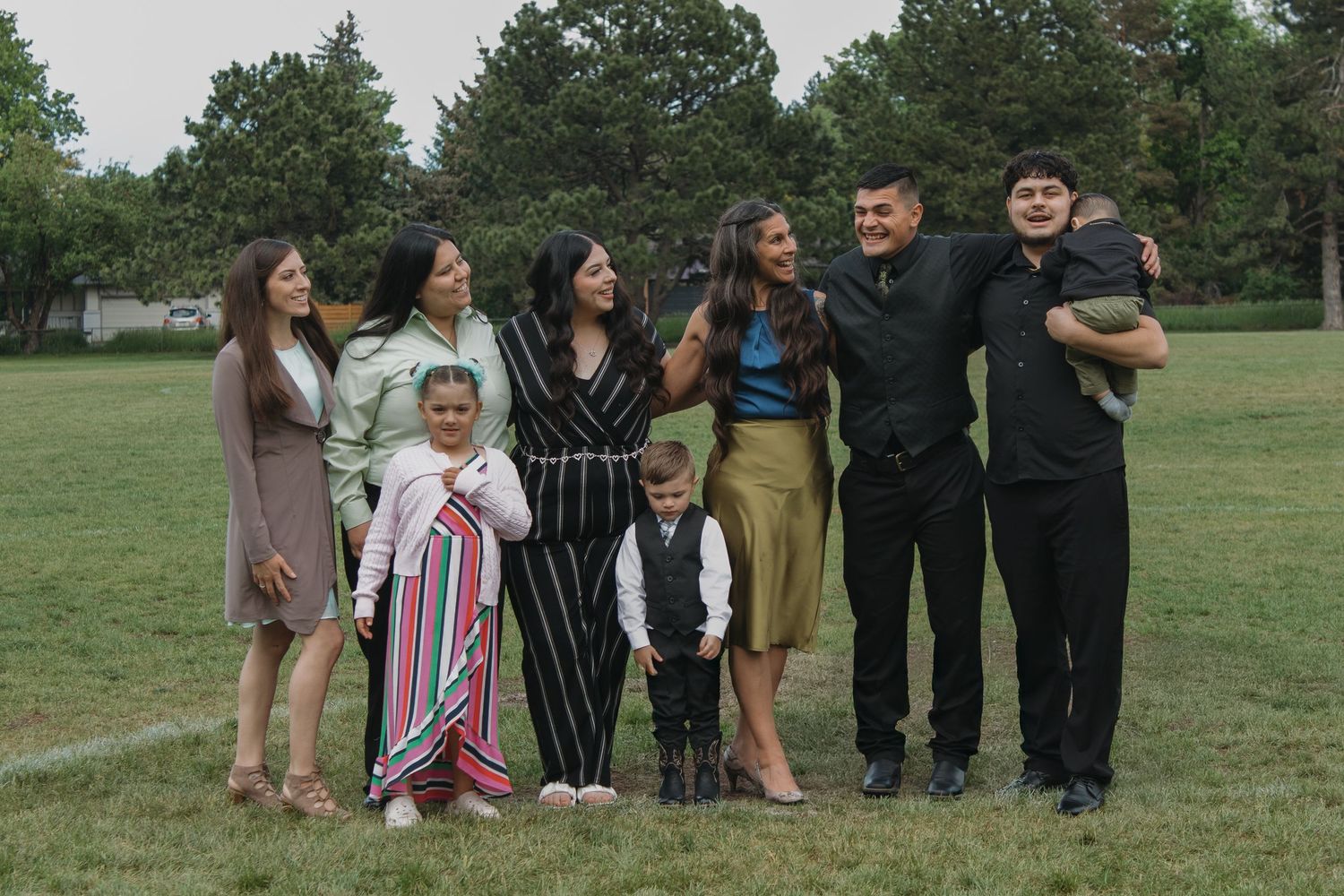 A group photo session takes place in a grassy field with trees in the background.
