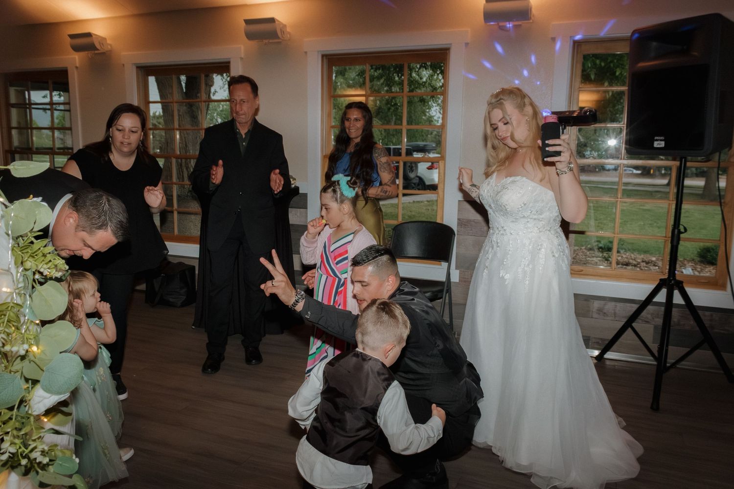 Wedding party dancing and celebrating together on a wooden dance floor at a reception venue.