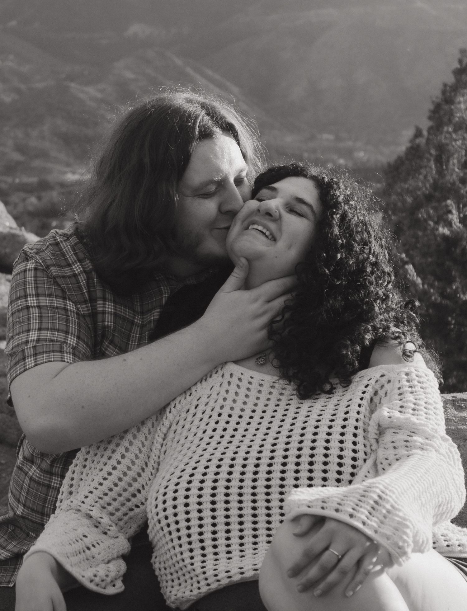 An intimate black and white portrait of a couple sharing a tender moment in the mountains.