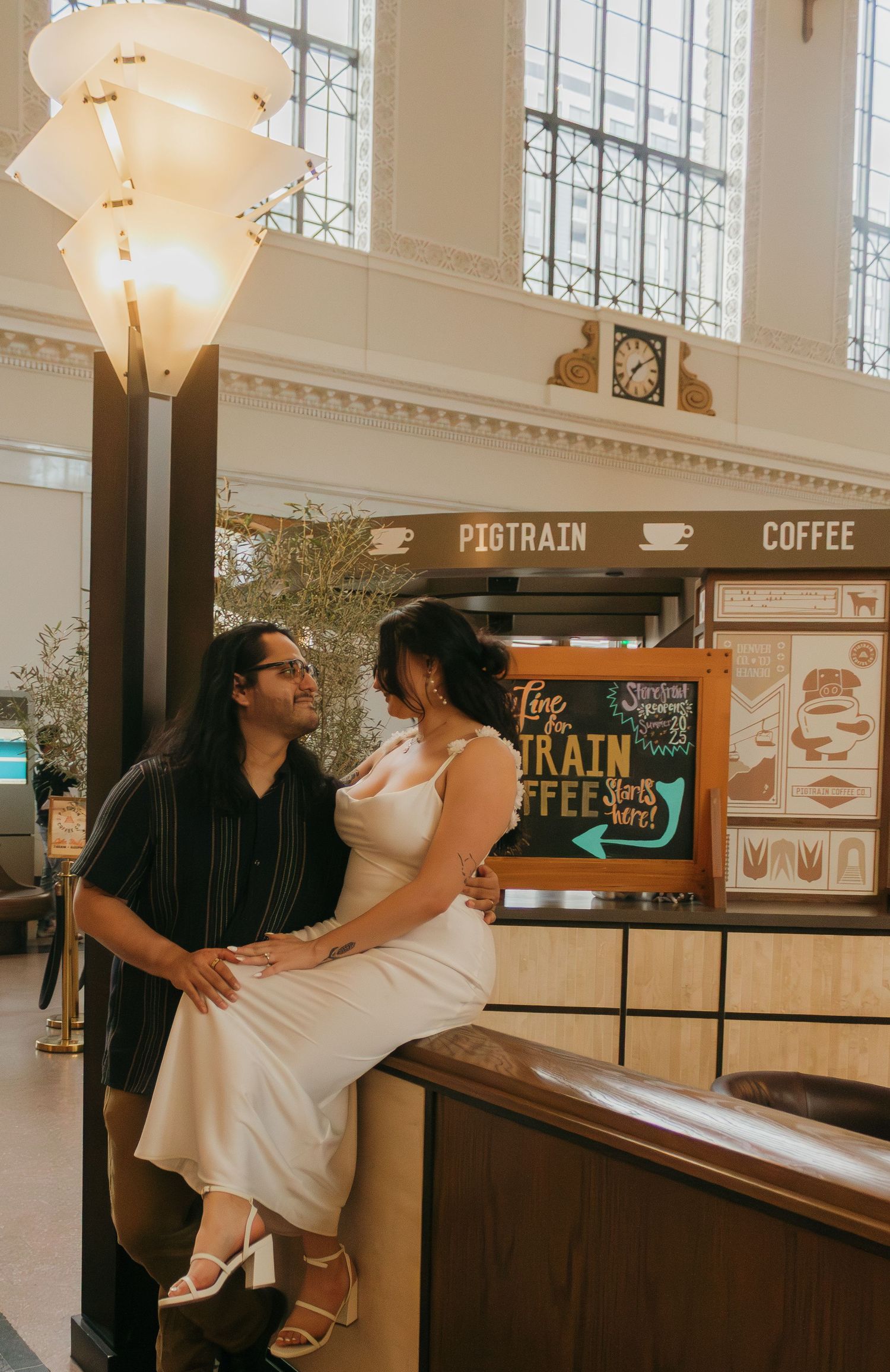 Couple shares intimate moment at vintage coffee shop counter with illuminated pendant light.