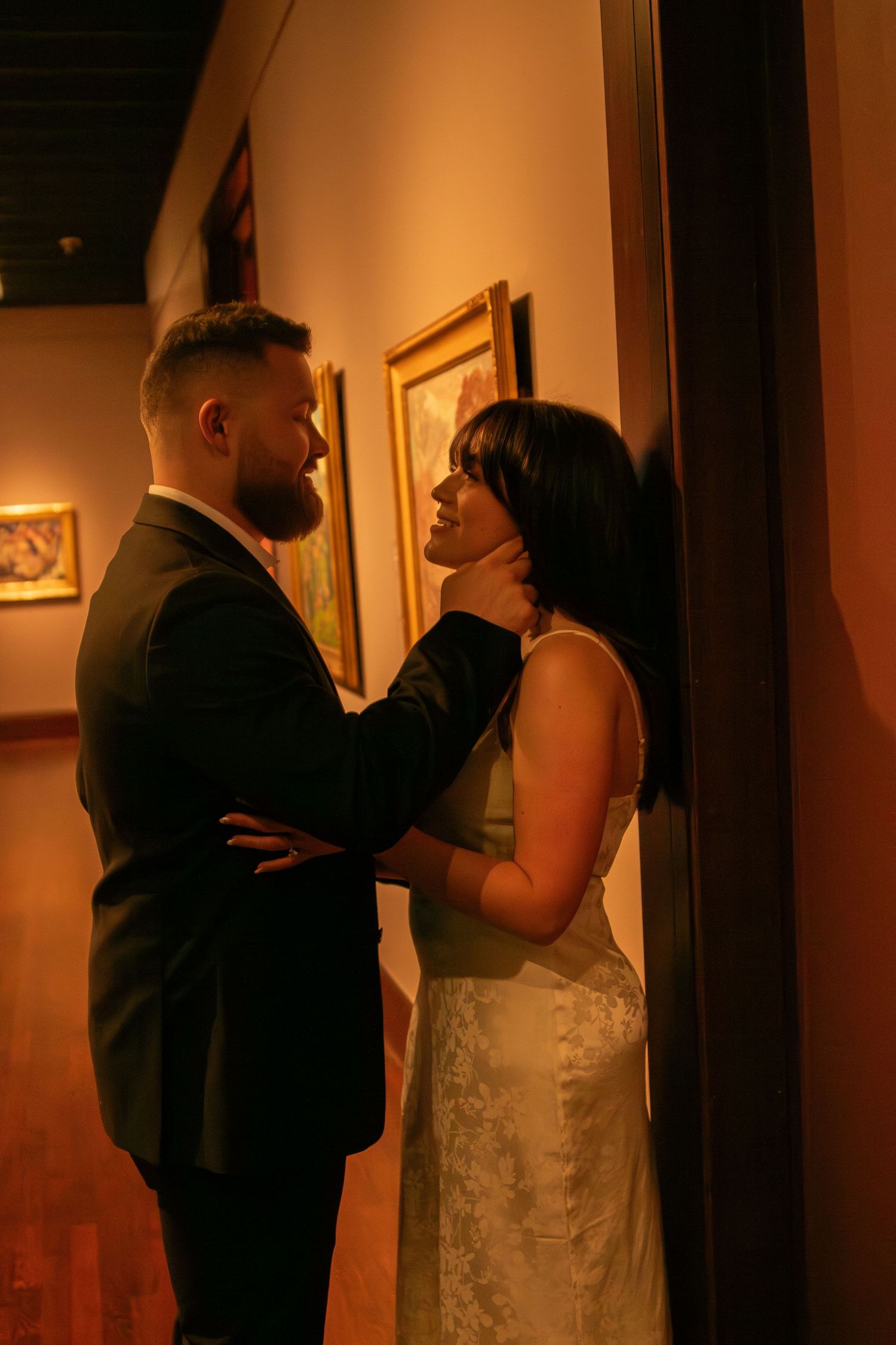 Couple in wedding attire sharing intimate moments in warm lighting.