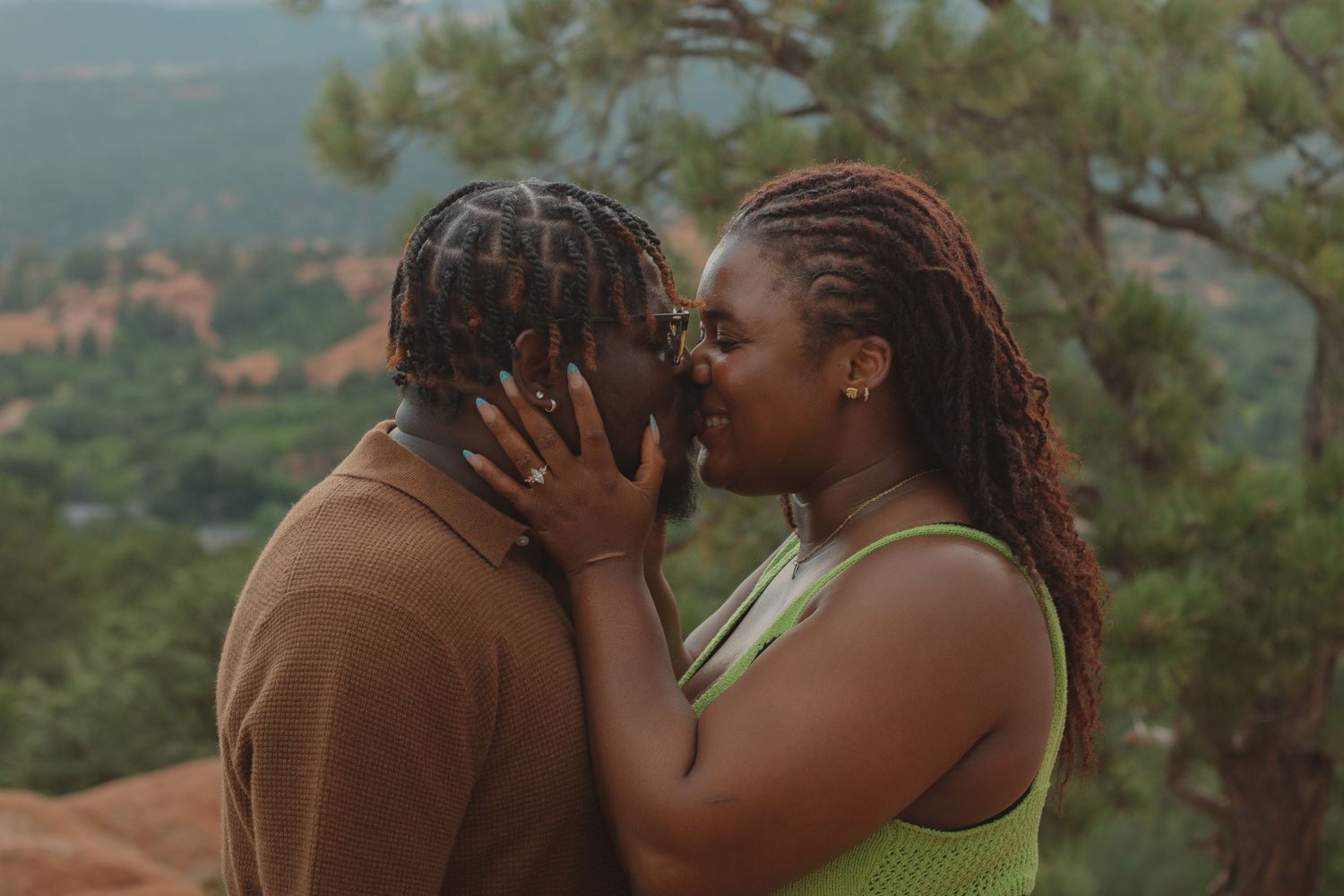 A romantic couple embraces against a backdrop of mountain scenery.