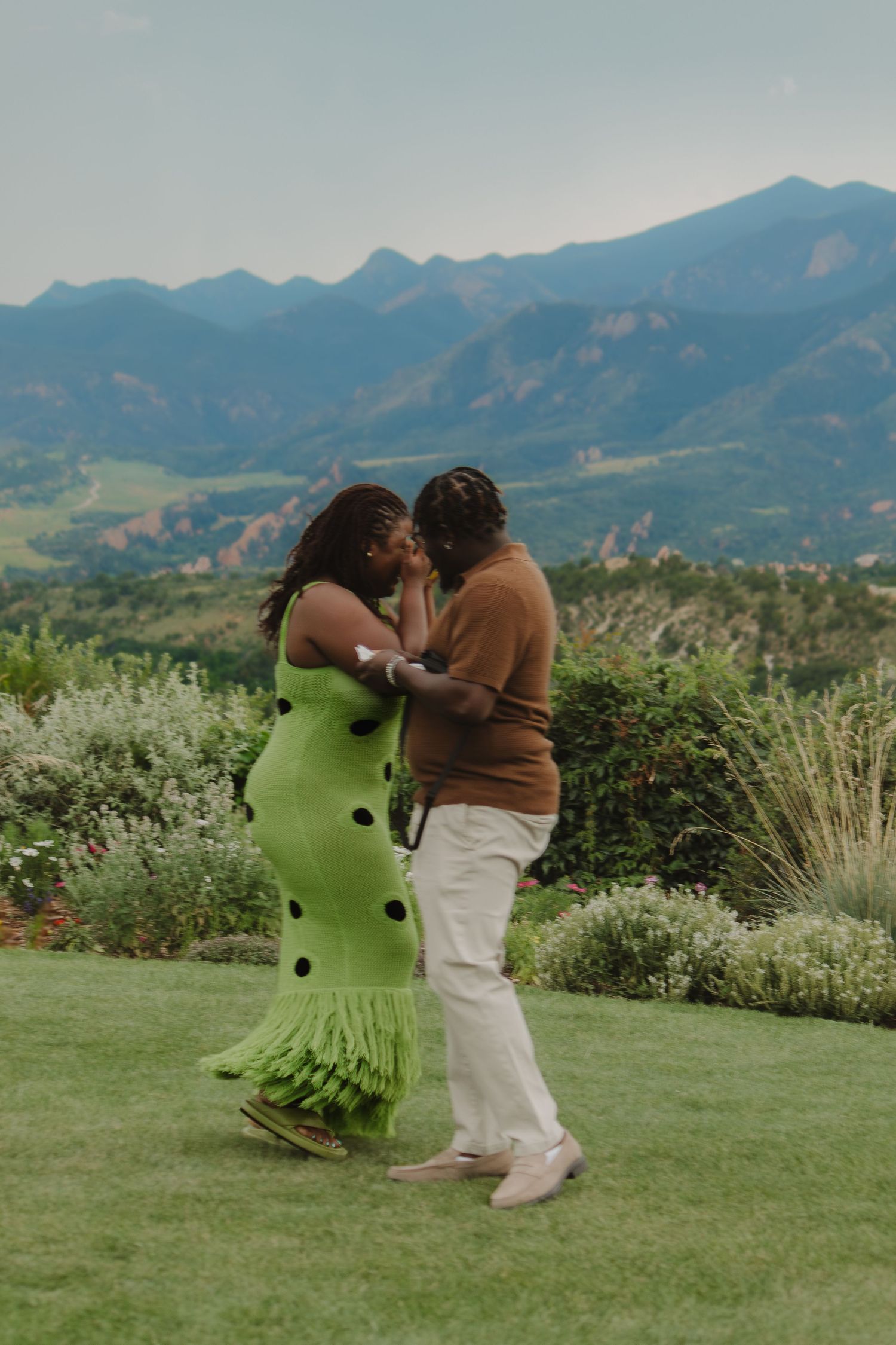Two people sharing a playful dance moment outdoors with mountains in the distance.