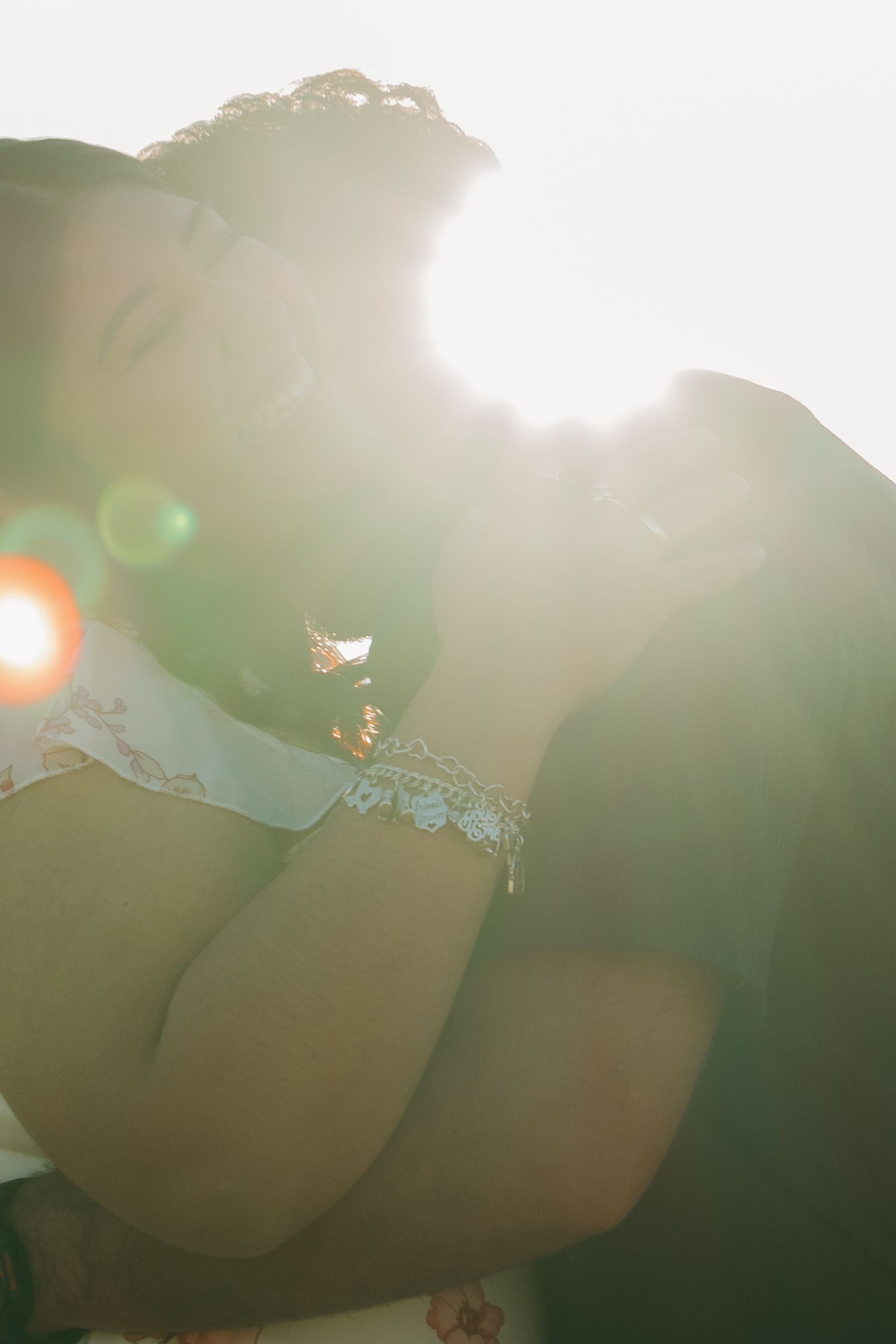 An artistic silhouette photograph shows sunlight flaring through delicate lace details on a wedding gown.