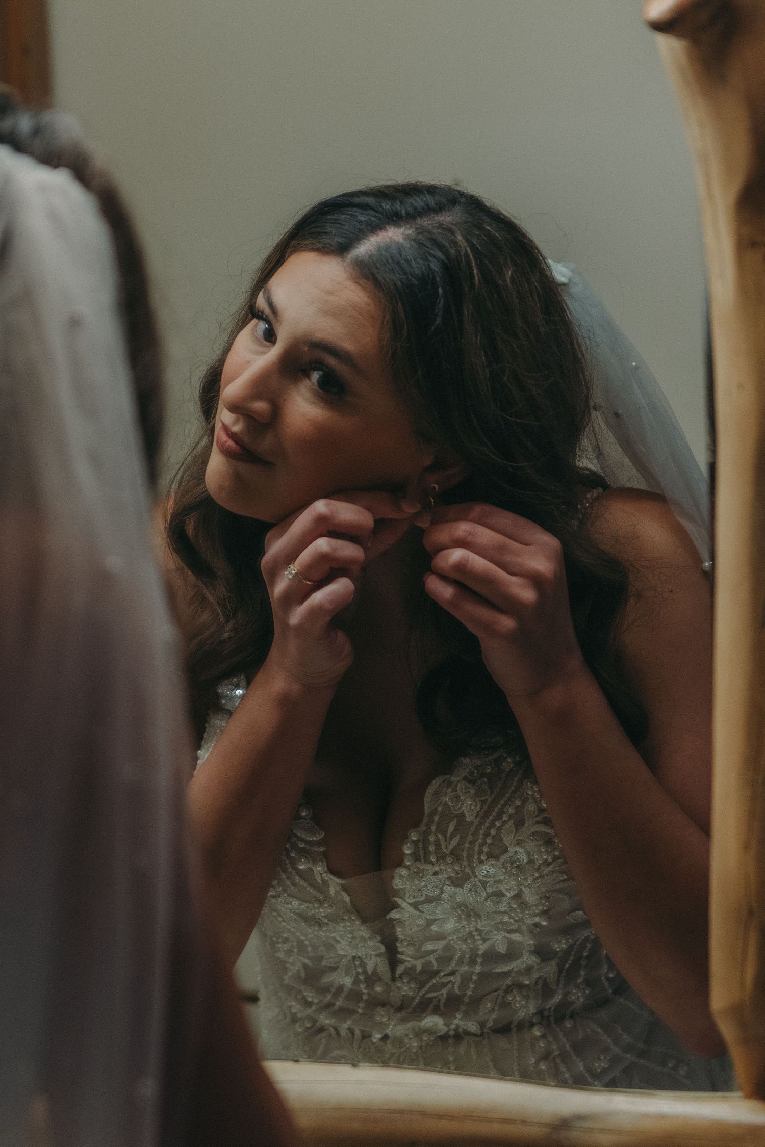 Close-up reflection of bridal preparations in a rustic wooden-framed mirror.
