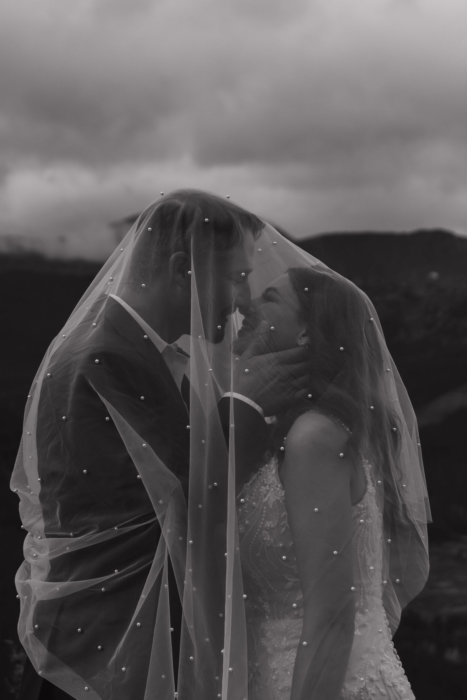 A delicate wedding veil flowing in the wind against a dramatic cloudy sky.