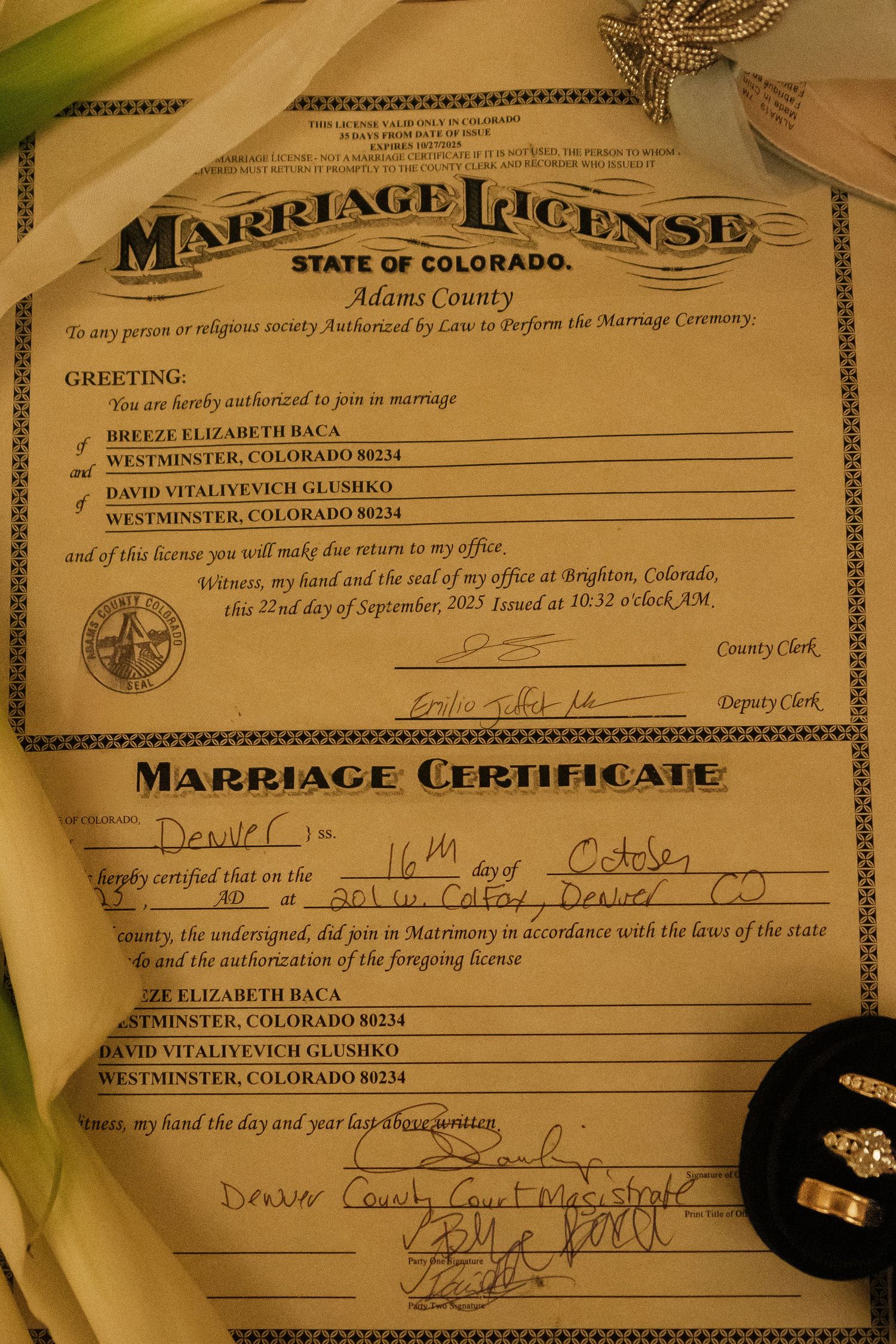Marriage license and certificate documents from the state of Colorado displayed on a textured surface.