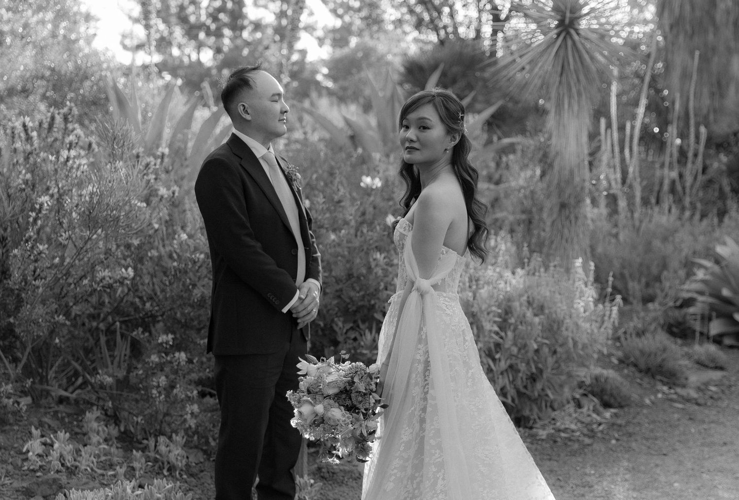 A romantic black and white wedding photo of a bride and groom standing in Walnut Creek, CA. Ruth Bancroft Garden setting with soft lighting.