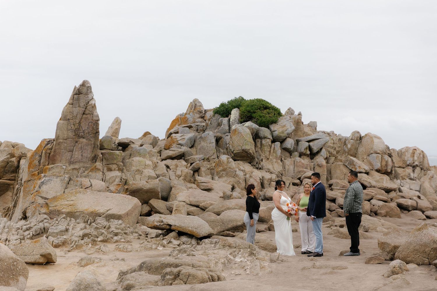 Visitors explore ancient stone ruins and archaeological remains on a rocky hilltop overlooking a scenic landscape.