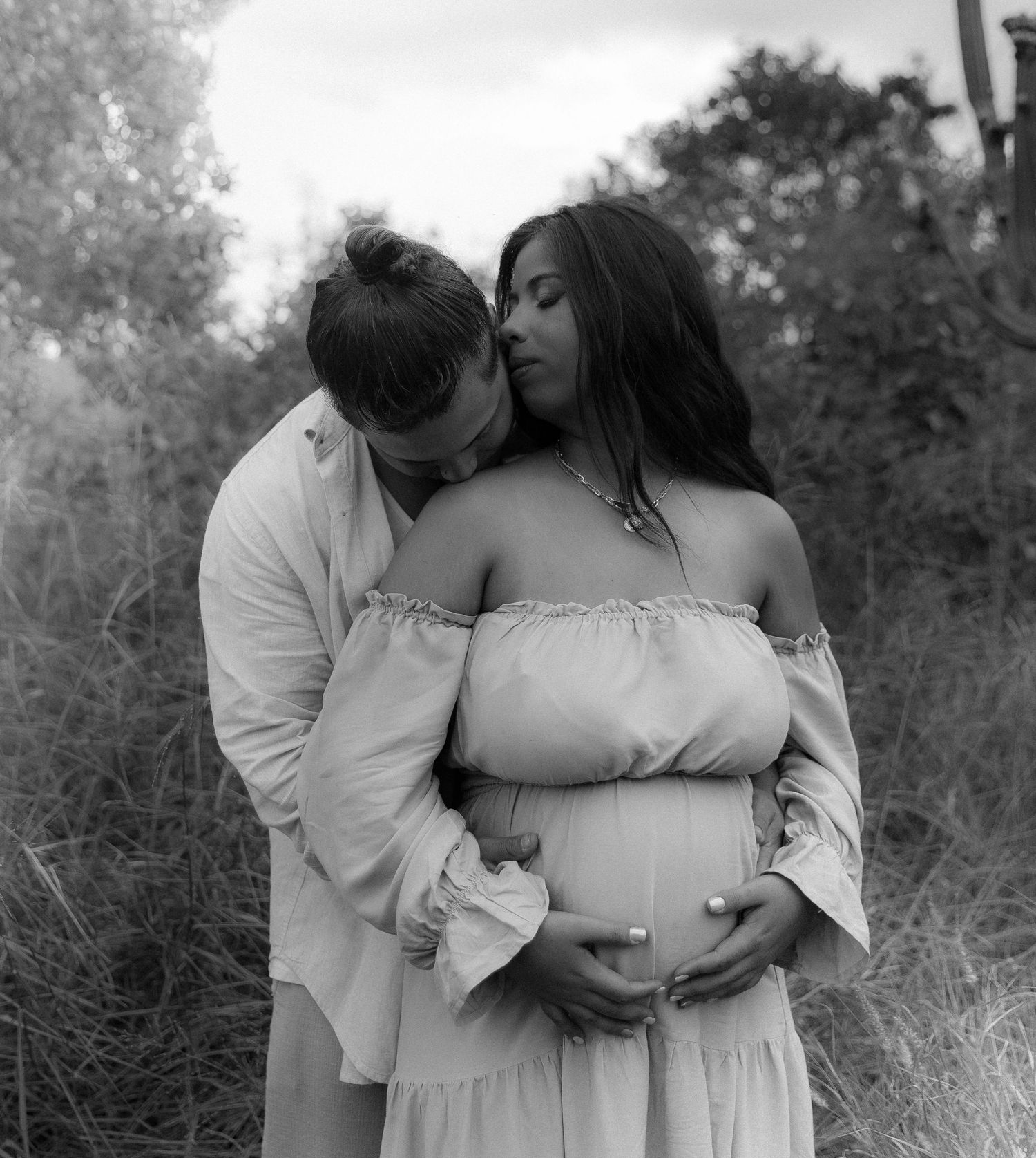 Black and white maternity photo sequence showing a tender embrace between expectant parents in an outdoor setting.