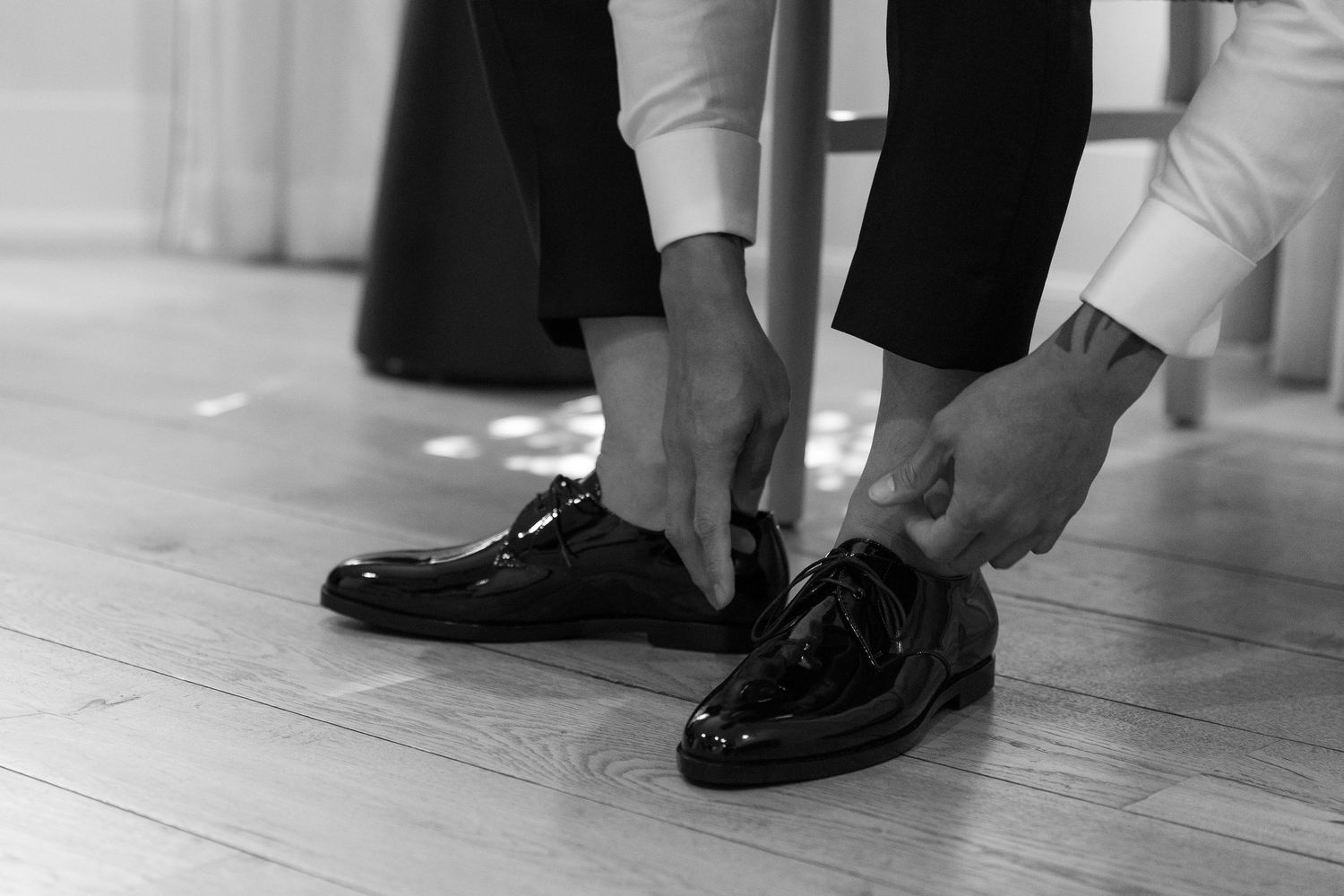 A row of formal black dress shoes and dress pants visible from ankle level on a light colored floor.
