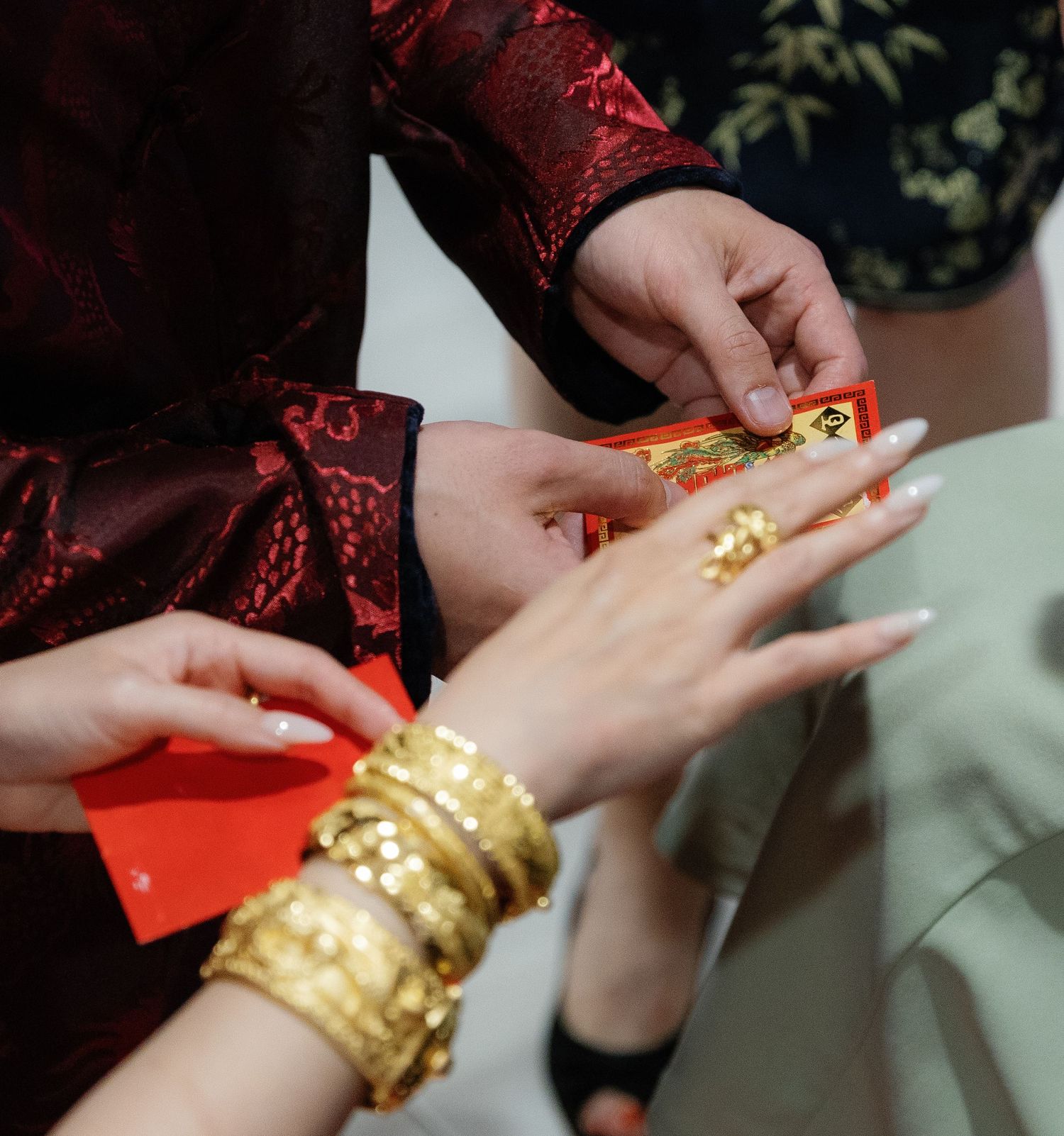 Traditional Chinese wedding ceremony showing hands exchanging gold bangles as part of cultural customs.
