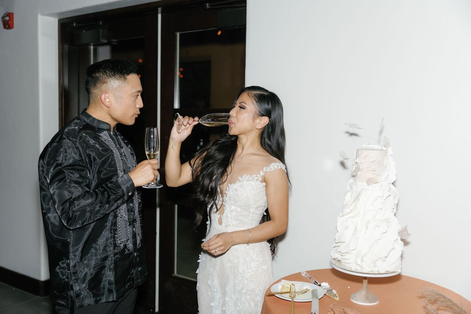 A couple in formal attire sharing intimate moments during what appears to be a wedding celebration.