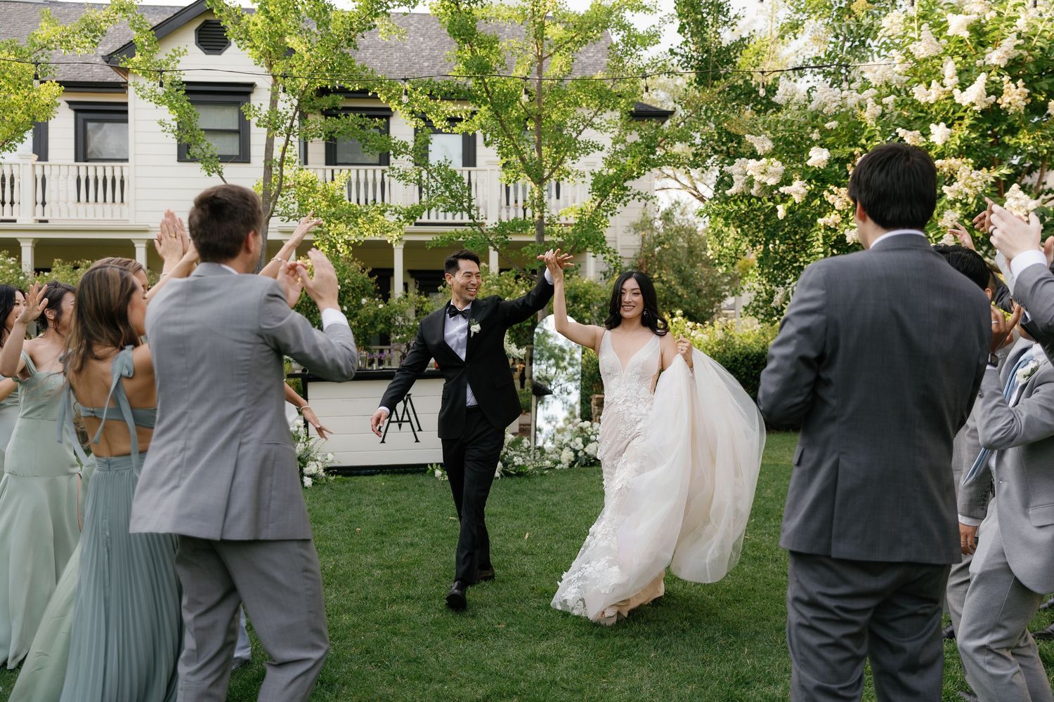 Wedding guests celebrate and dance outdoors on a green lawn during a summer garden reception in Mc Arthur Place Hotel in Sonoma, CA
