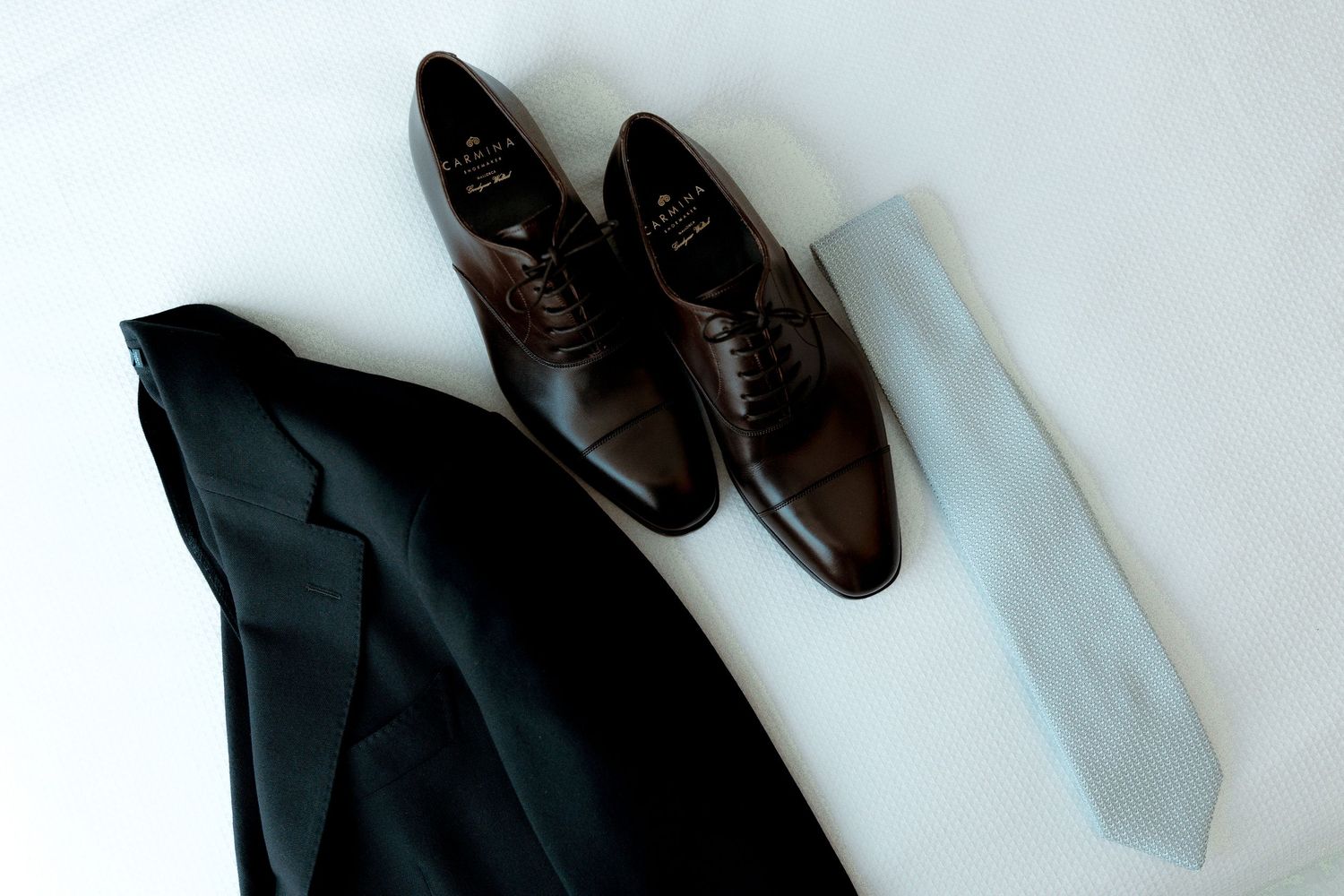 A collection of dark formal men's dress shoes arranged neatly against a light background.