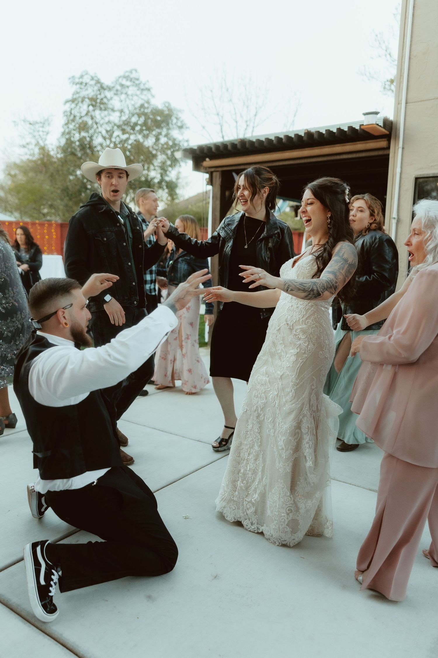 Wedding guests dance and celebrate on an outdoor patio during a festive reception.