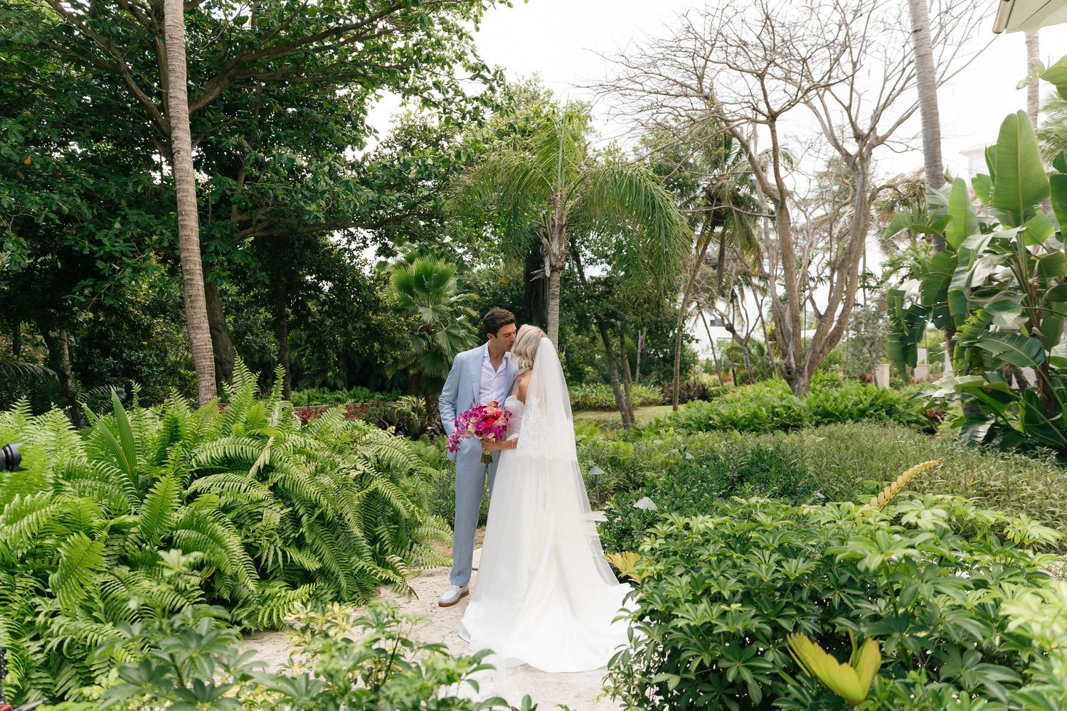 Couple shares romantic moments in lush garden setting during outdoor wedding photoshoot.