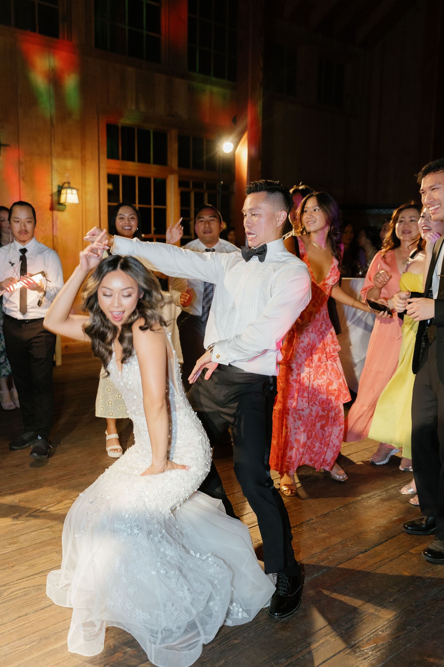 Wedding guests dance and celebrate on a wooden dance floor at an evening reception.