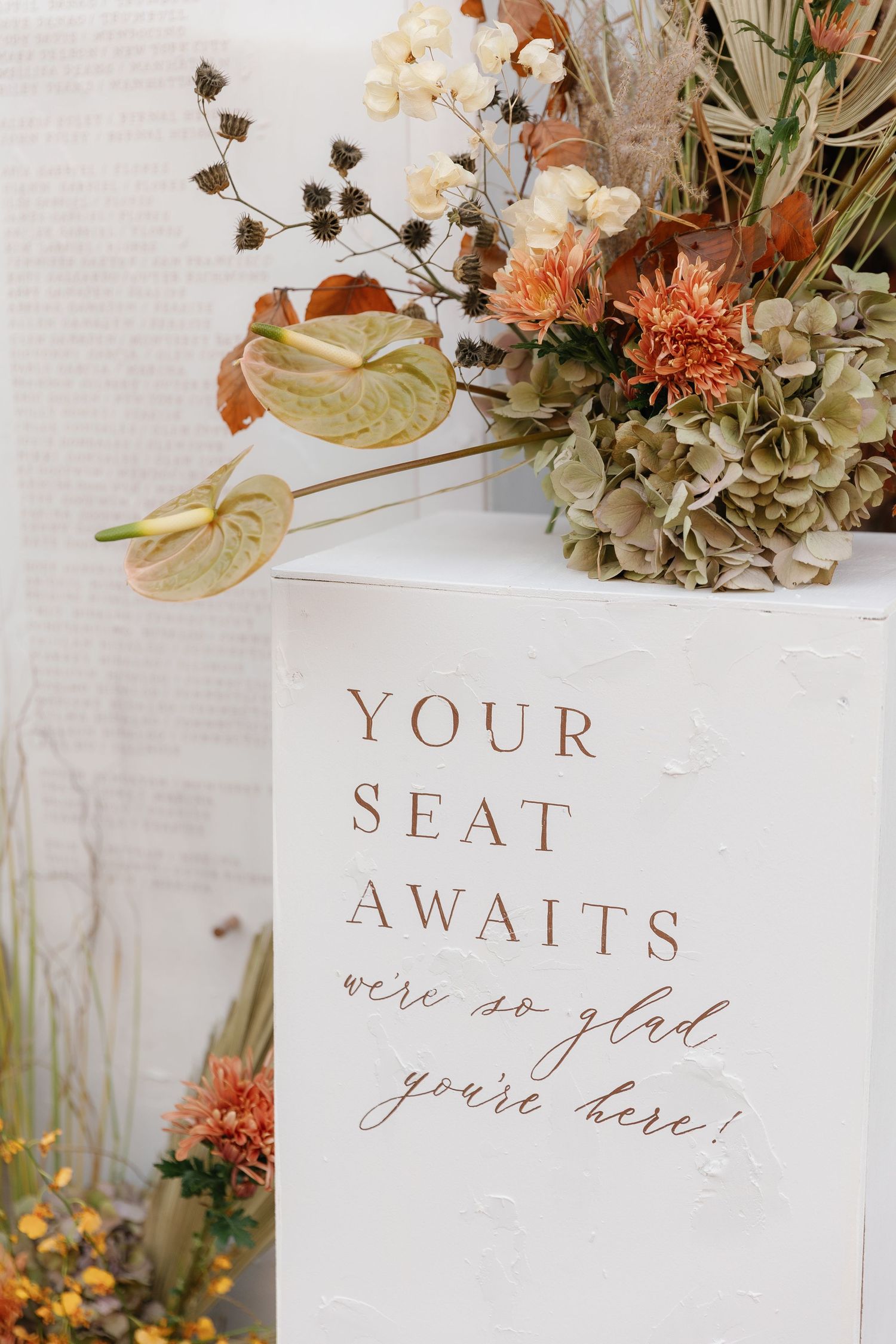 Elegant wedding place cards with calligraphy text displayed among peach and white floral arrangements.