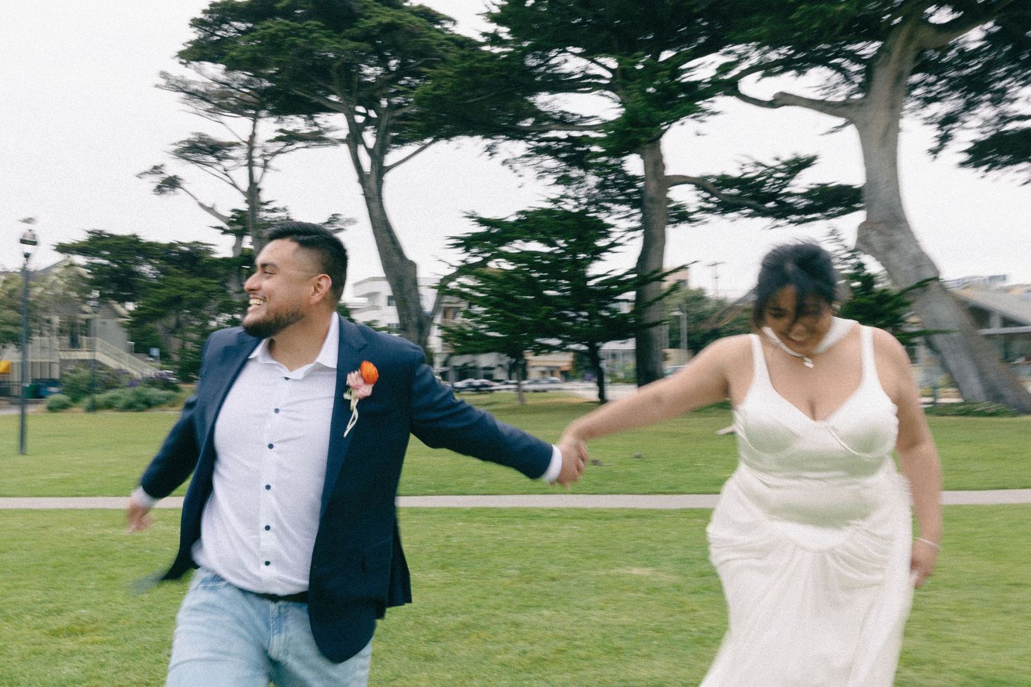 Joyful wedding couple shares playful moments in a scenic outdoor setting with cypress trees.