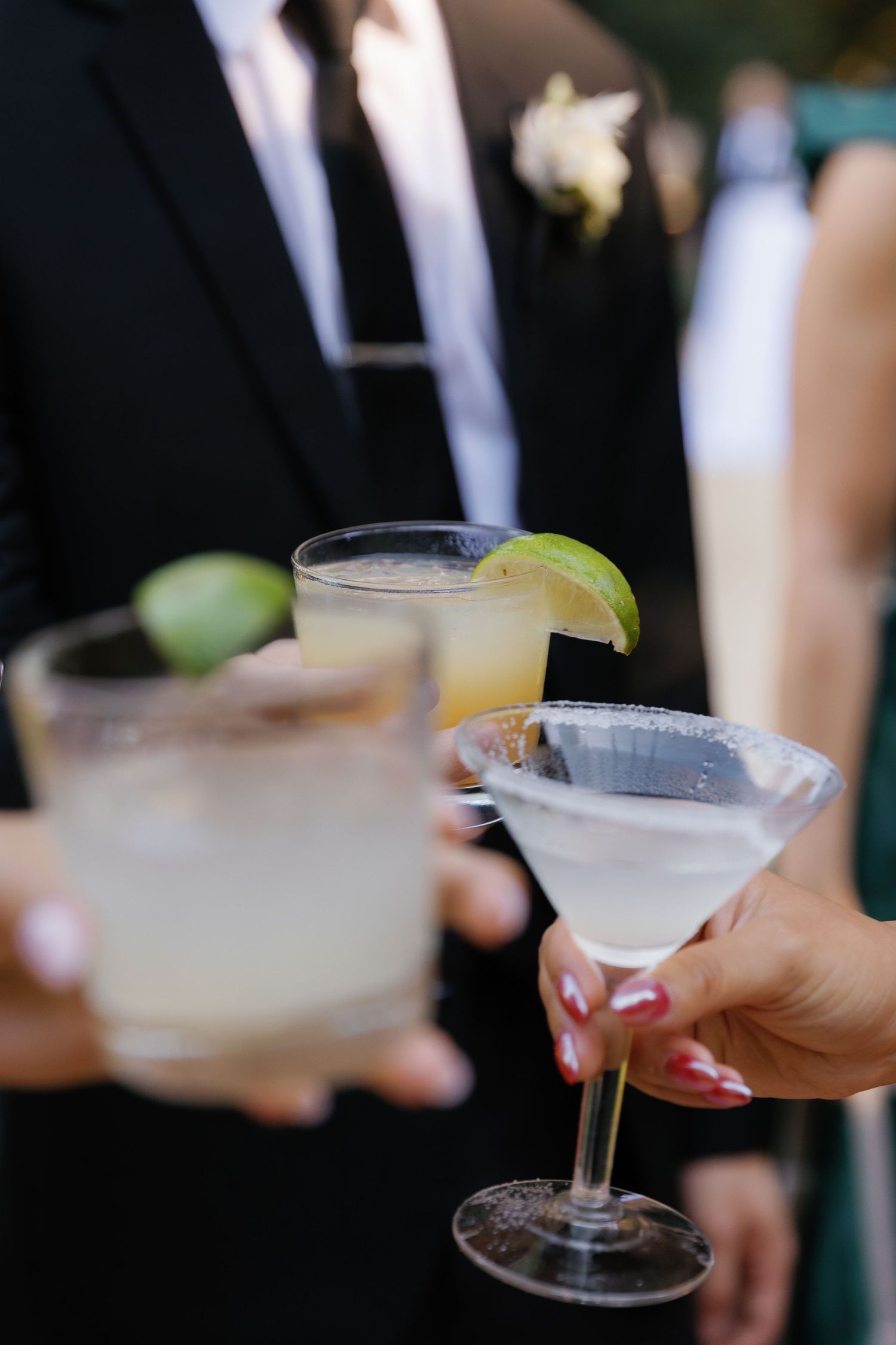 Elegant cocktail glasses with lime garnishes being served at a formal event.
