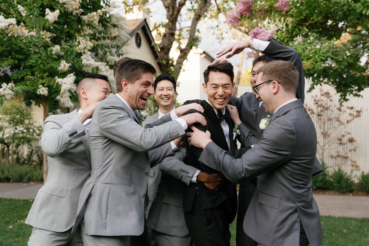 A group of groomsmen in gray suits playfully pose together in a sequence of candid moments outdoors.