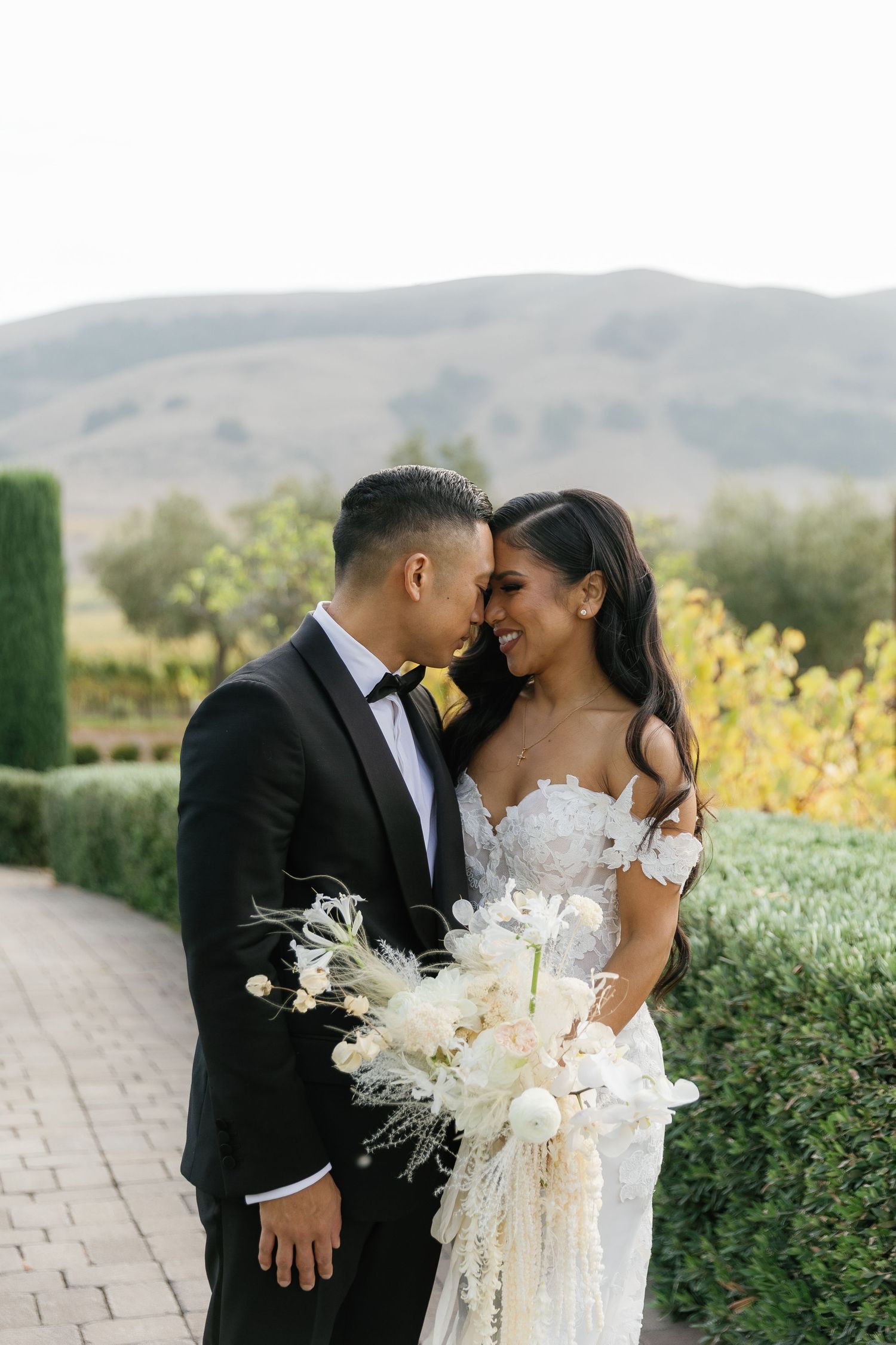 A romantic wedding couple shares intimate moments against a backdrop of rolling hills and blooming yellow flowers.