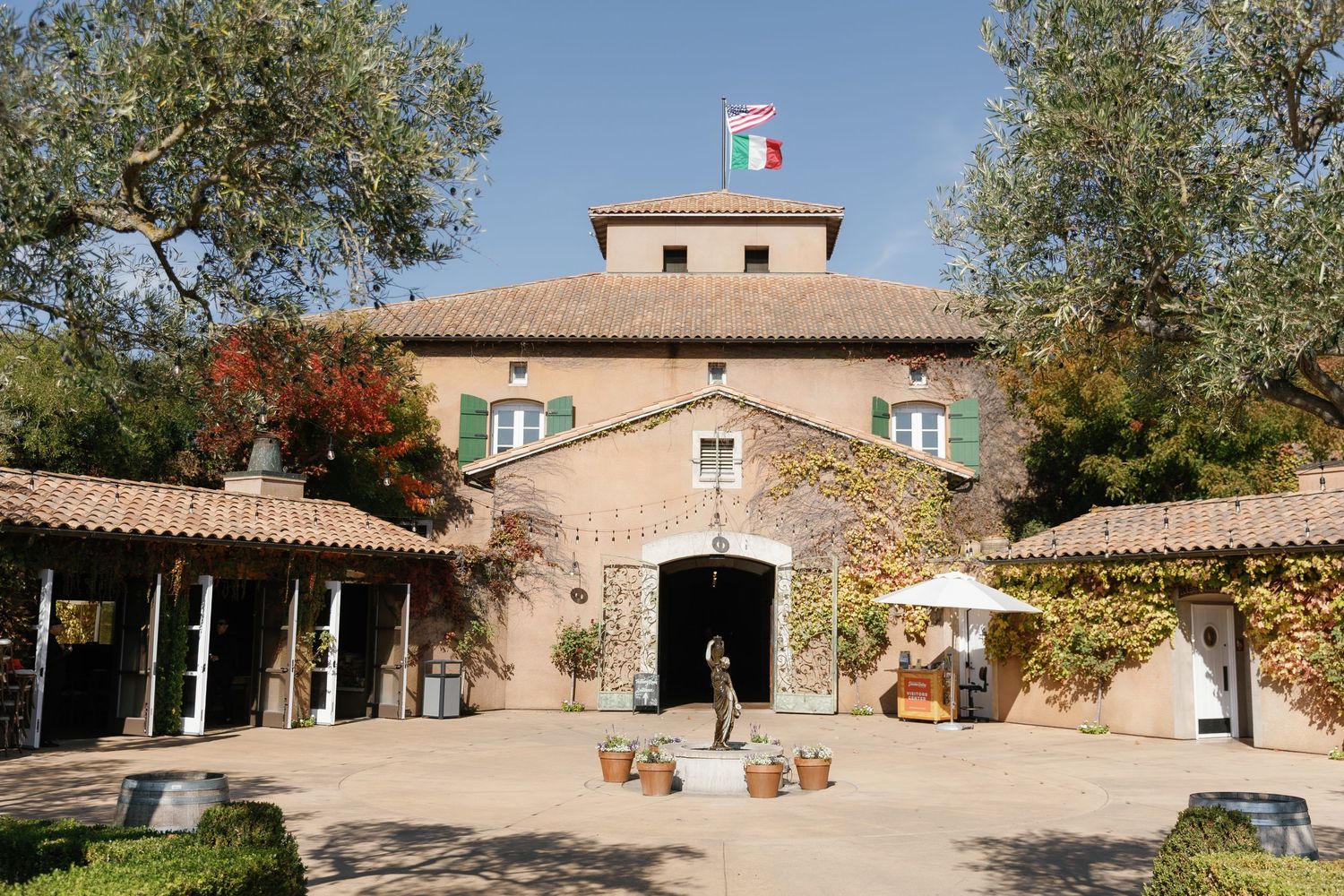 Mediterranean style villa with pink stucco exterior, olive trees, and French and Italian flags flying from the tower.