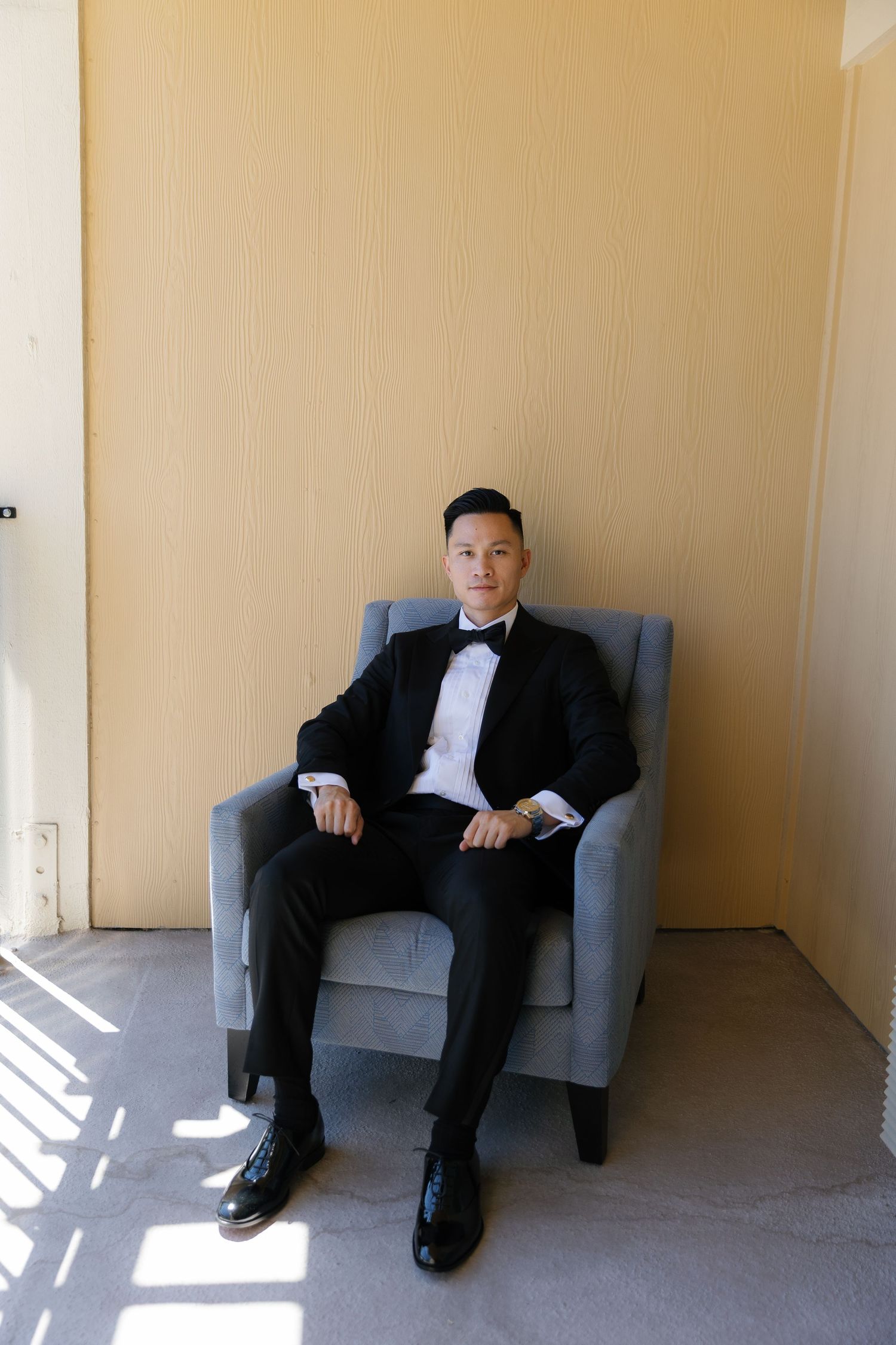 A sequence of three photos showing a person in a suit sitting in a grey armchair against a beige wall.