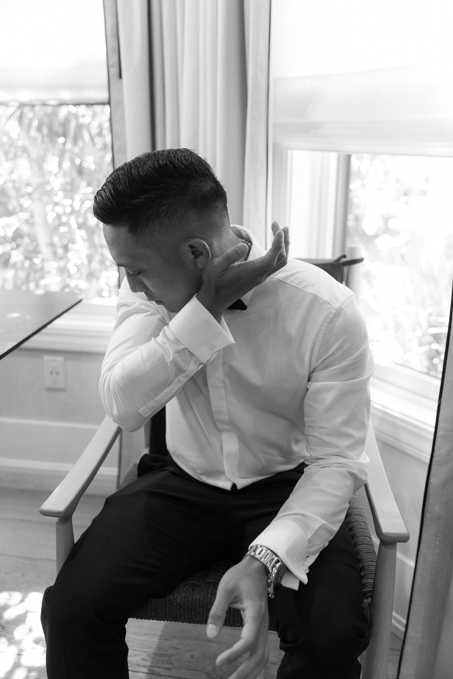Black and white photo series showing a person in a white shirt and dark pants sitting by a window in various poses.