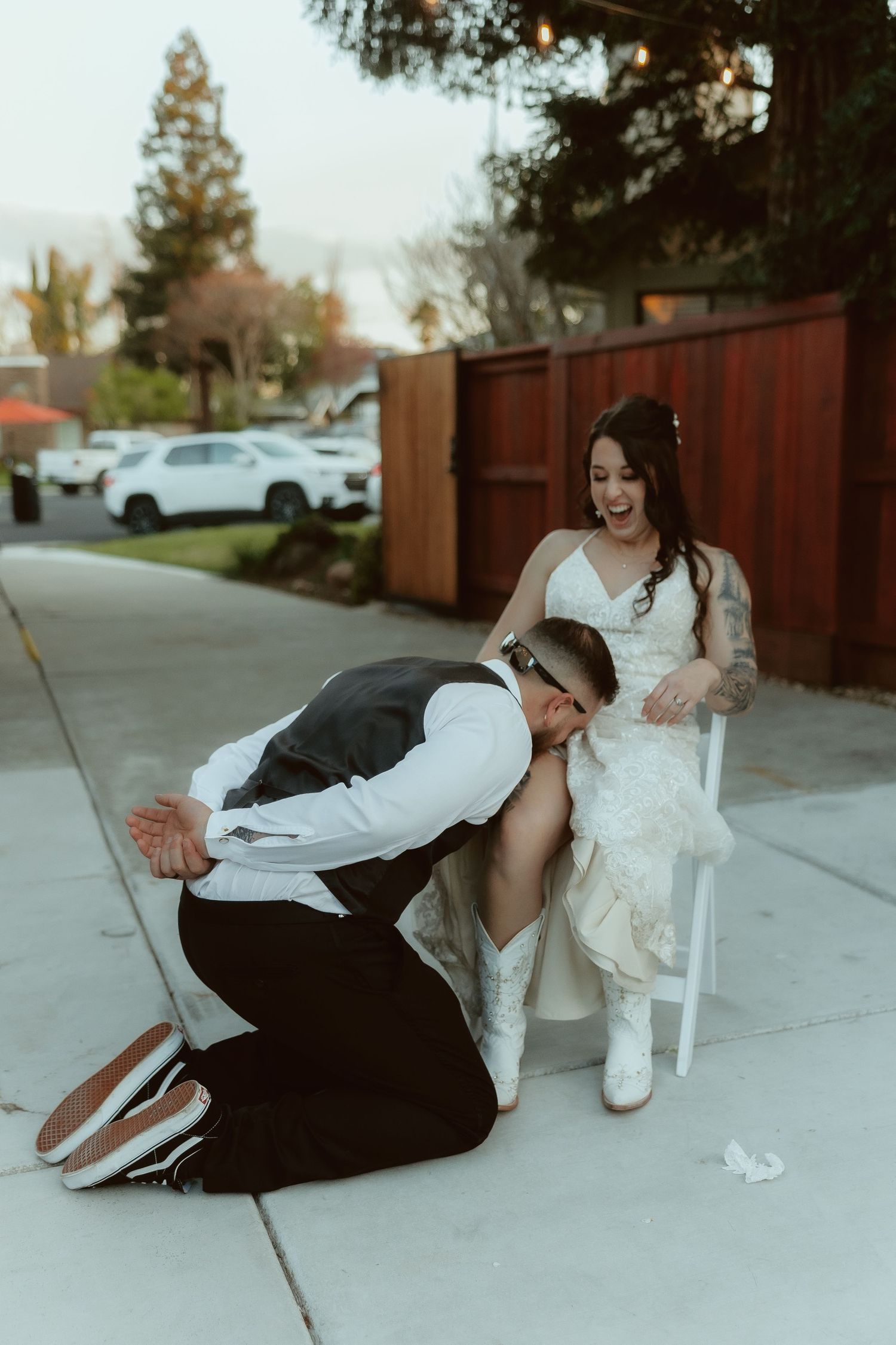 A playful sequence shows a couple falling over together on a sidewalk while laughing and having fun during their wedding shoot.