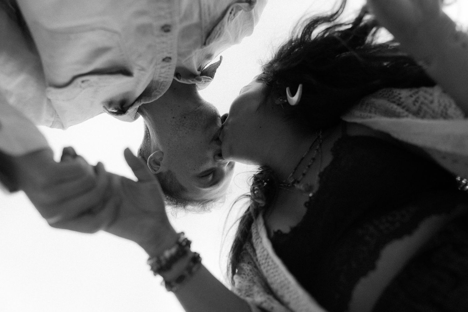 A high contrast black and white artistic photograph showing two figures in an intimate close-up composition.
