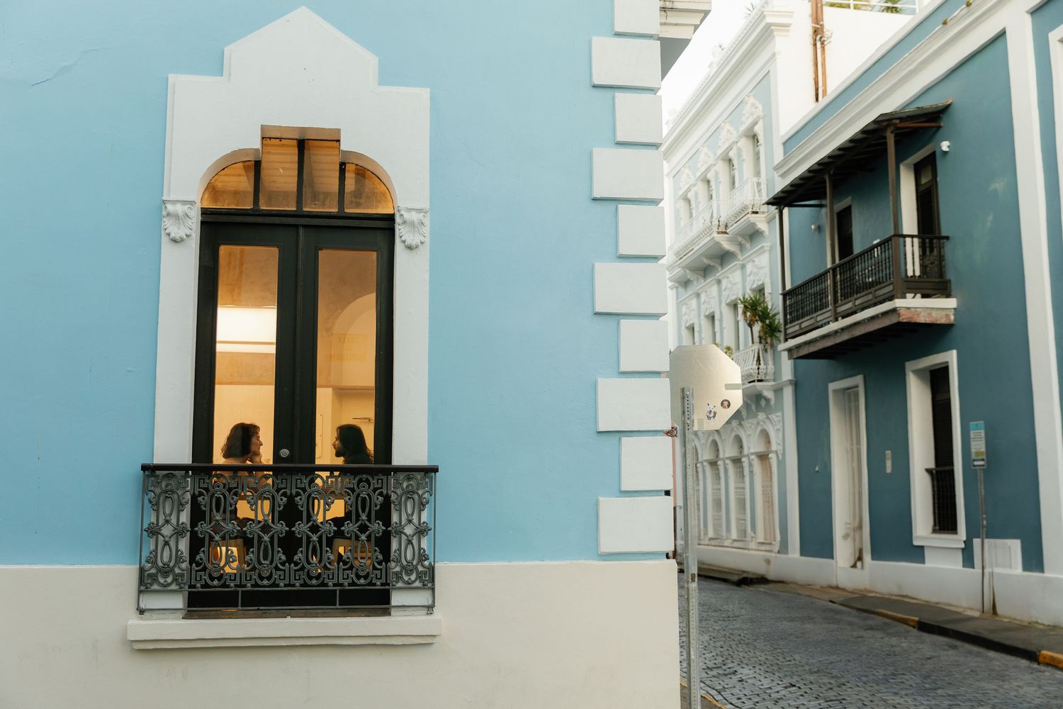 Architectural details of a light blue and white building facade with ornate windows and balconies in a historic style.